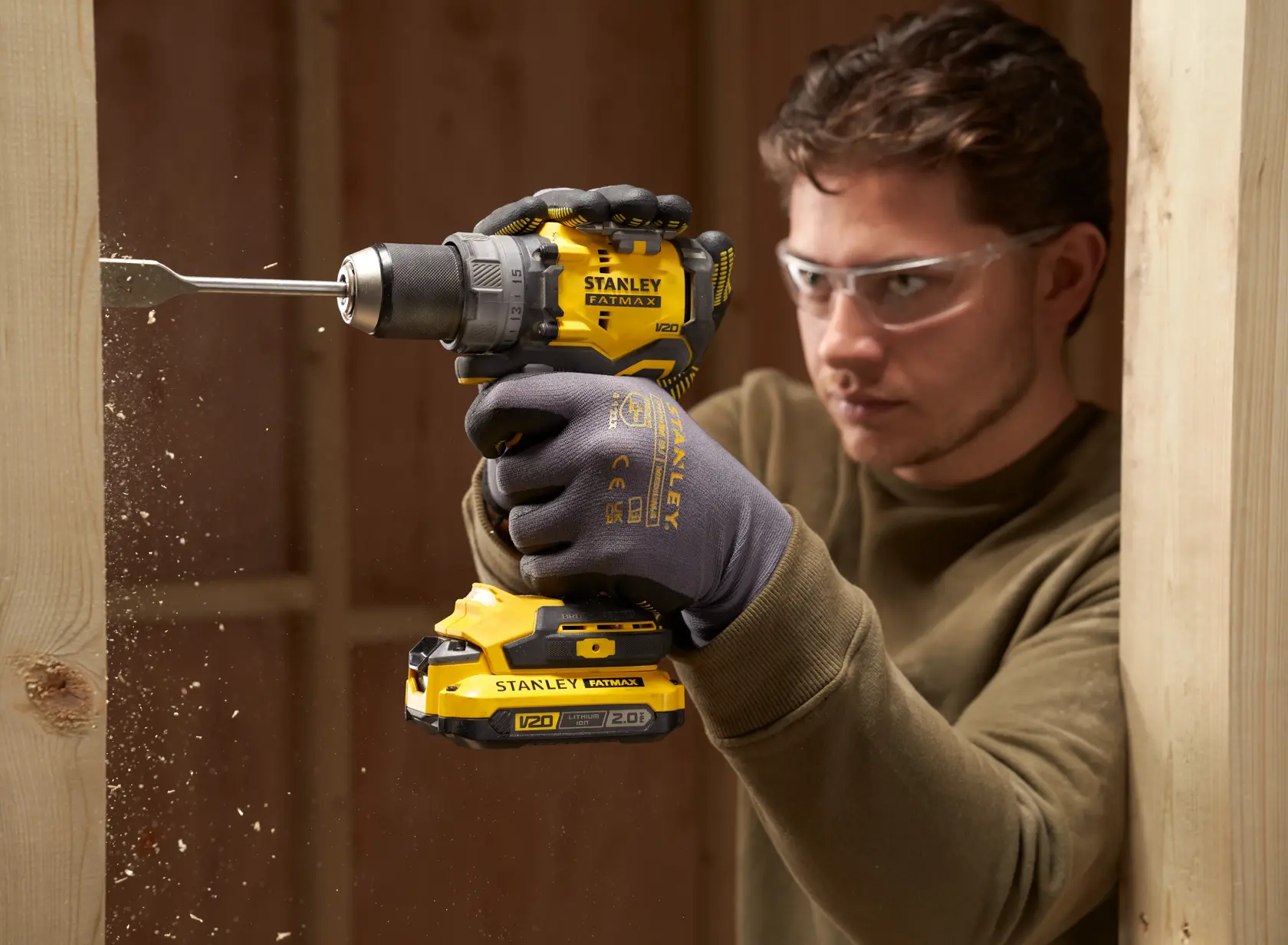 Foto des STANLEY SFMCD725B Akku-Bohrschraubers im Einsatz, bohrt in Holz, gelb-schwarzes Design.