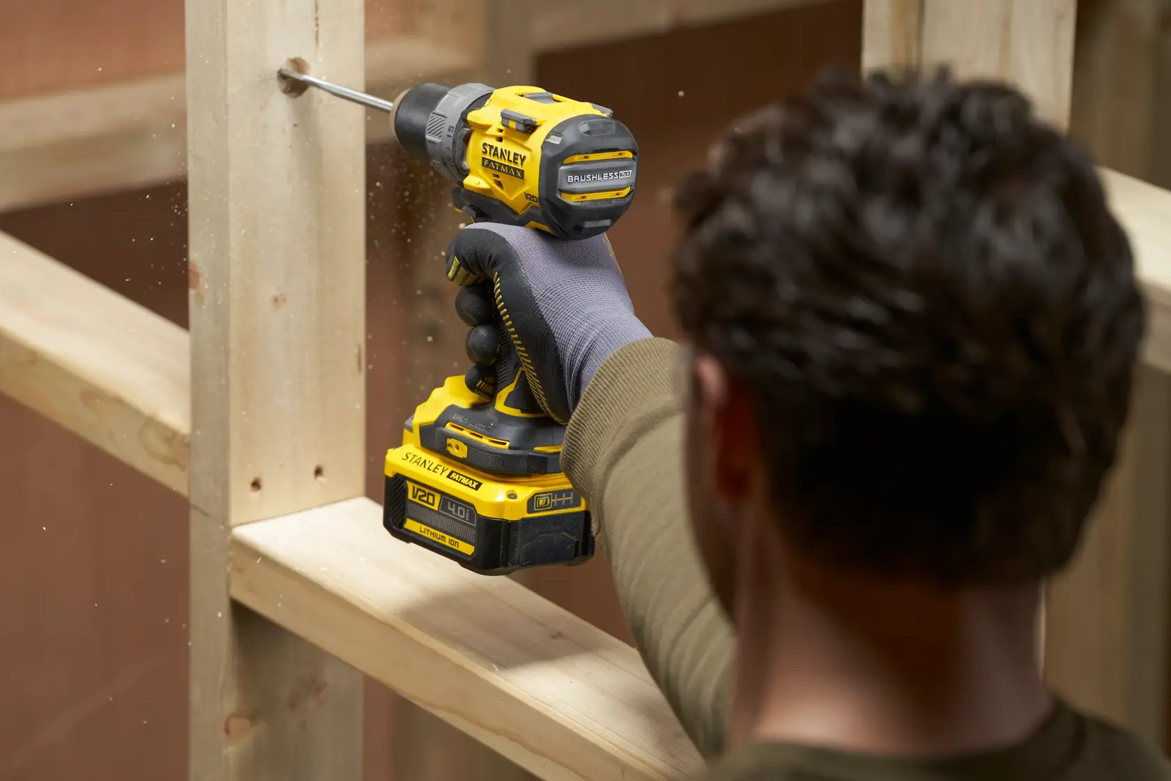 Foto des STANLEY SFMCD725B Akku-Bohrschraubers beim Bohren in Holz, Seitenansicht, schwarz-gelbes Design.