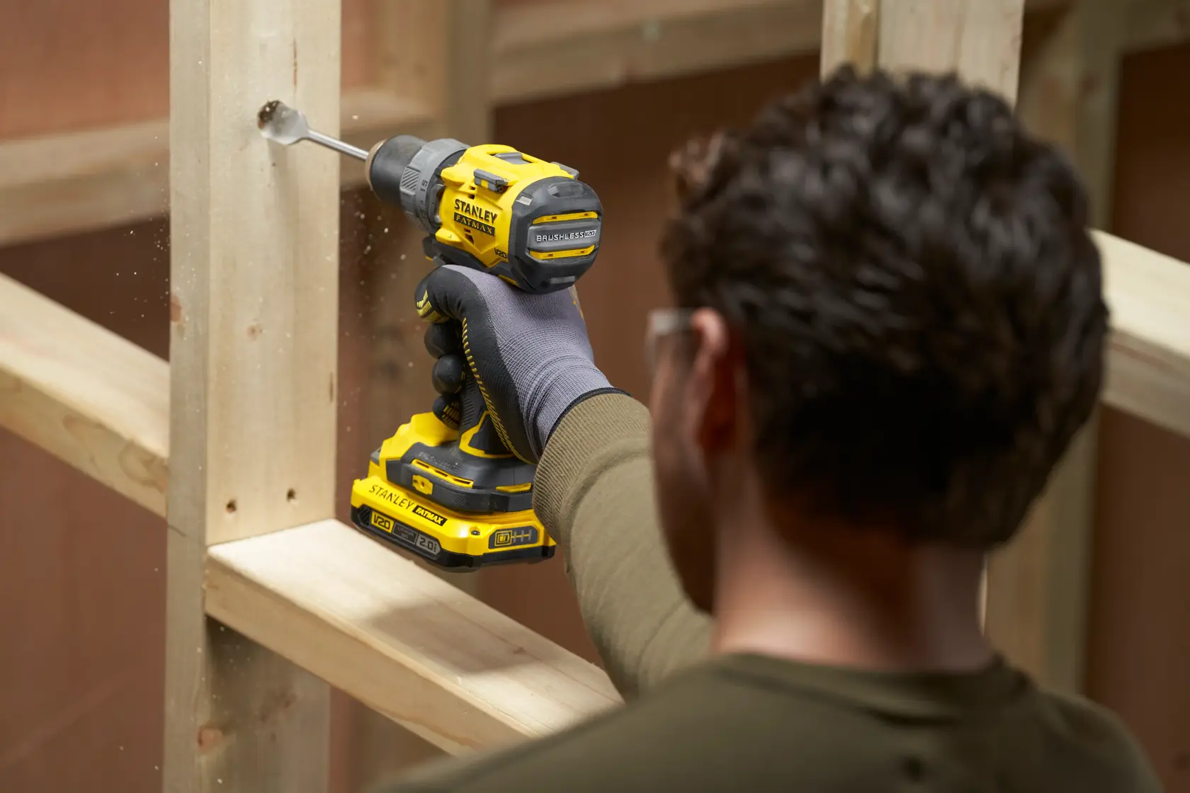 STANLEY SFMCD725D2K Akku-Bohrmaschine beim Bohren in Holz, Baustelleneinsatz, Seitenansicht.