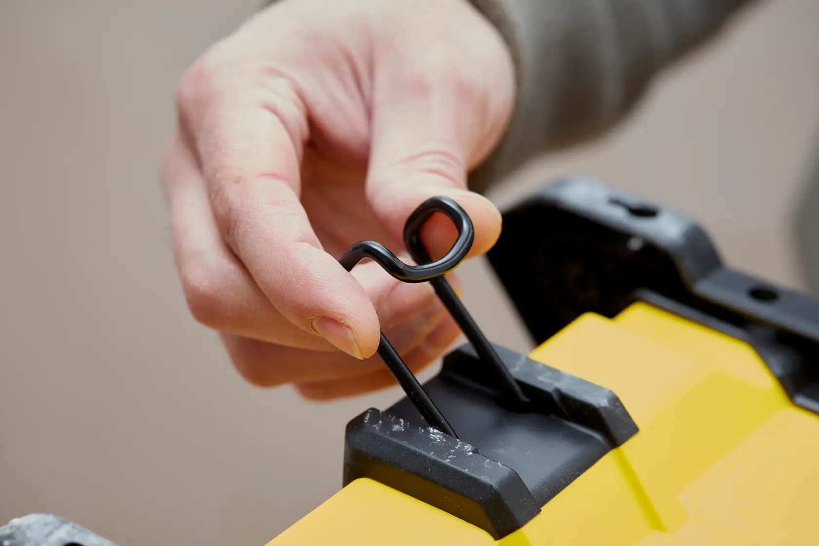 STANLEY SFMCE001B close-up of hand using black metal latch on yellow product surface.