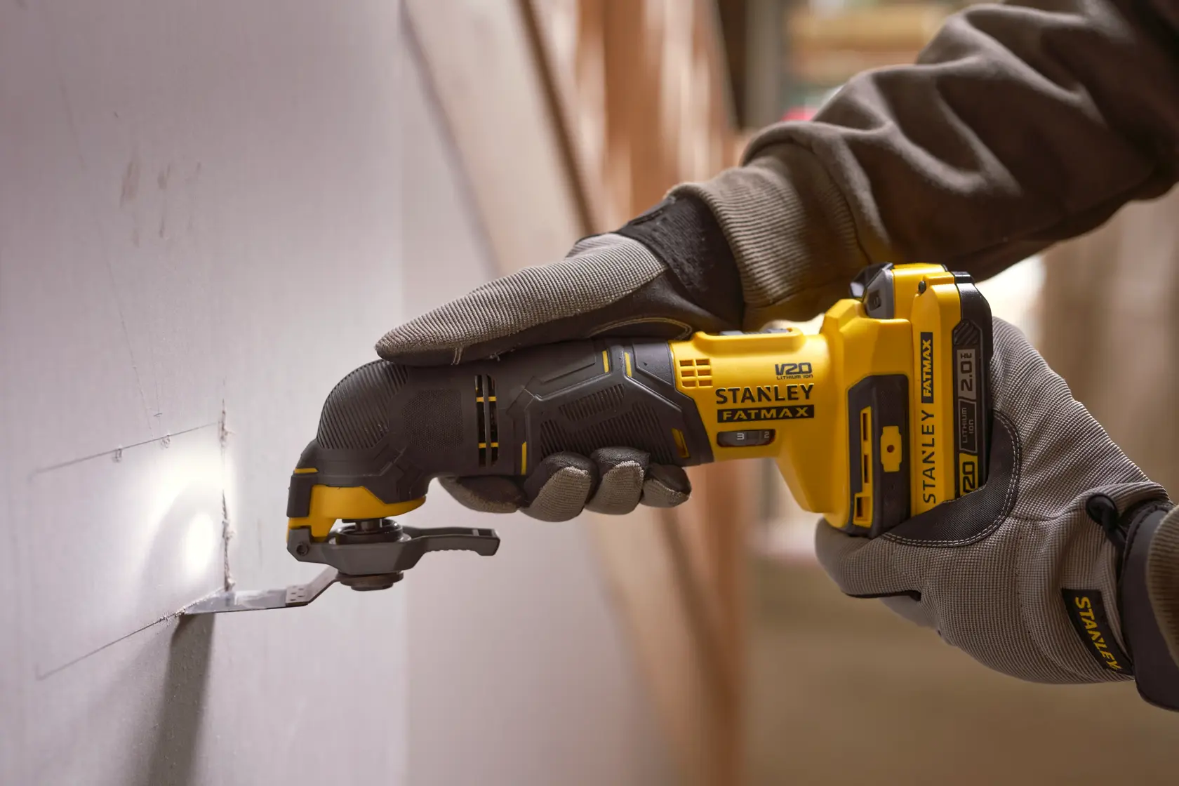 STANLEY SFMCE500D1K kabelloses oszillierendes Multitool schneidet Gipskarton, Nahaufnahme im Einsatz.