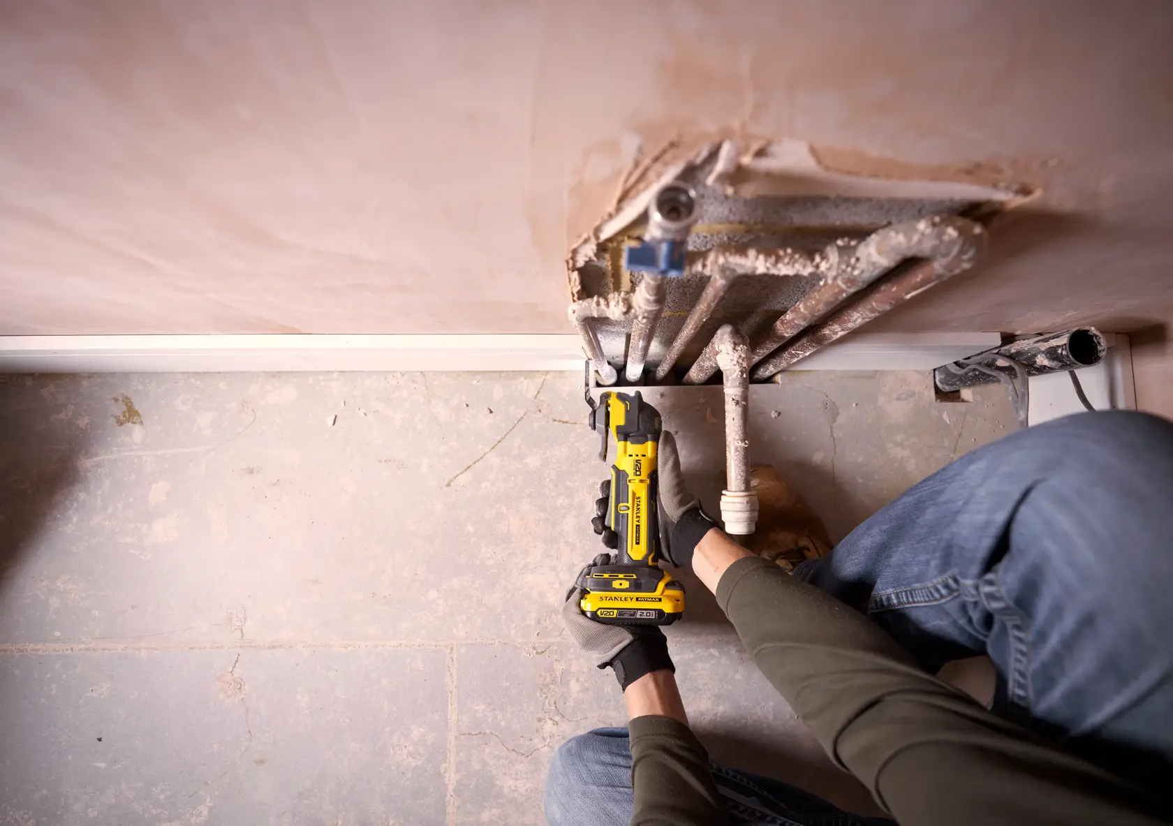 Photo of STANLEY SFMCE510B reciprocating saw used to cut pipes near wall, close-up view.