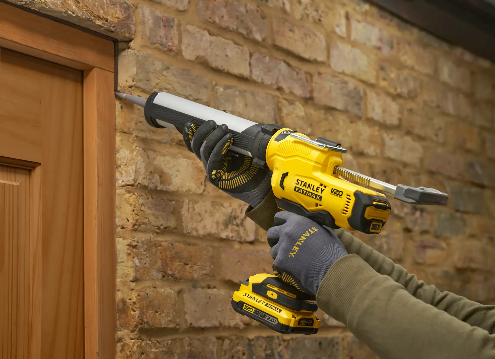 STANLEY SFMCE600B Kartuschenpistole zum Versiegeln eines Holzrahmens an einer Ziegelwand.