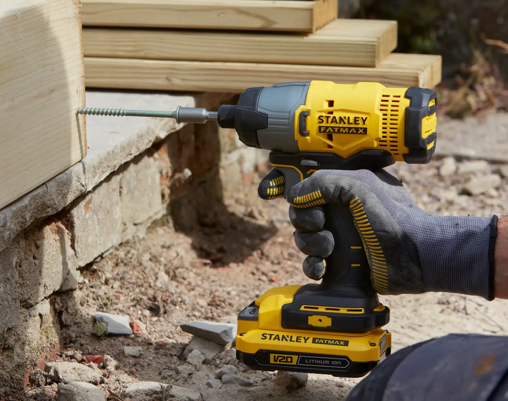 STANLEY SFMCF800C2K cordless impact driver in use driving screw into wood, close-up angle outdoors.