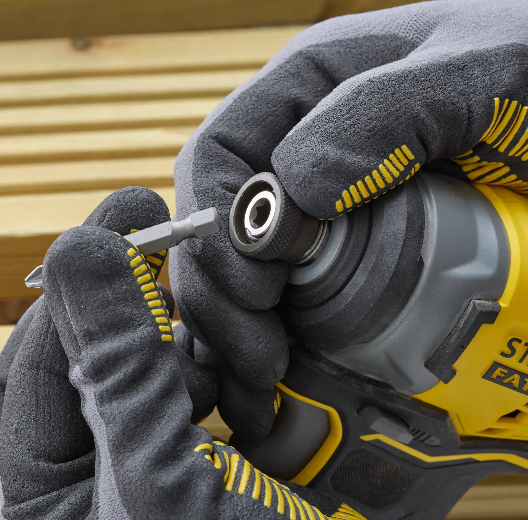 Photo of STANLEY SFMCF810B impact driver close-up, gloved hands inserting a screwdriver bit.