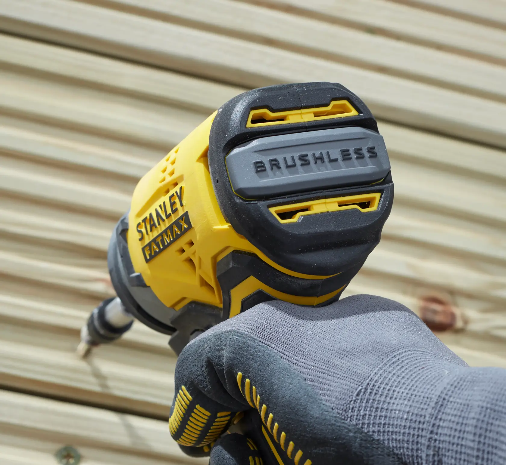 STANLEY SFMCF810D2K impact driver with brushless motor, close-up view, held by gloved hand against wood.