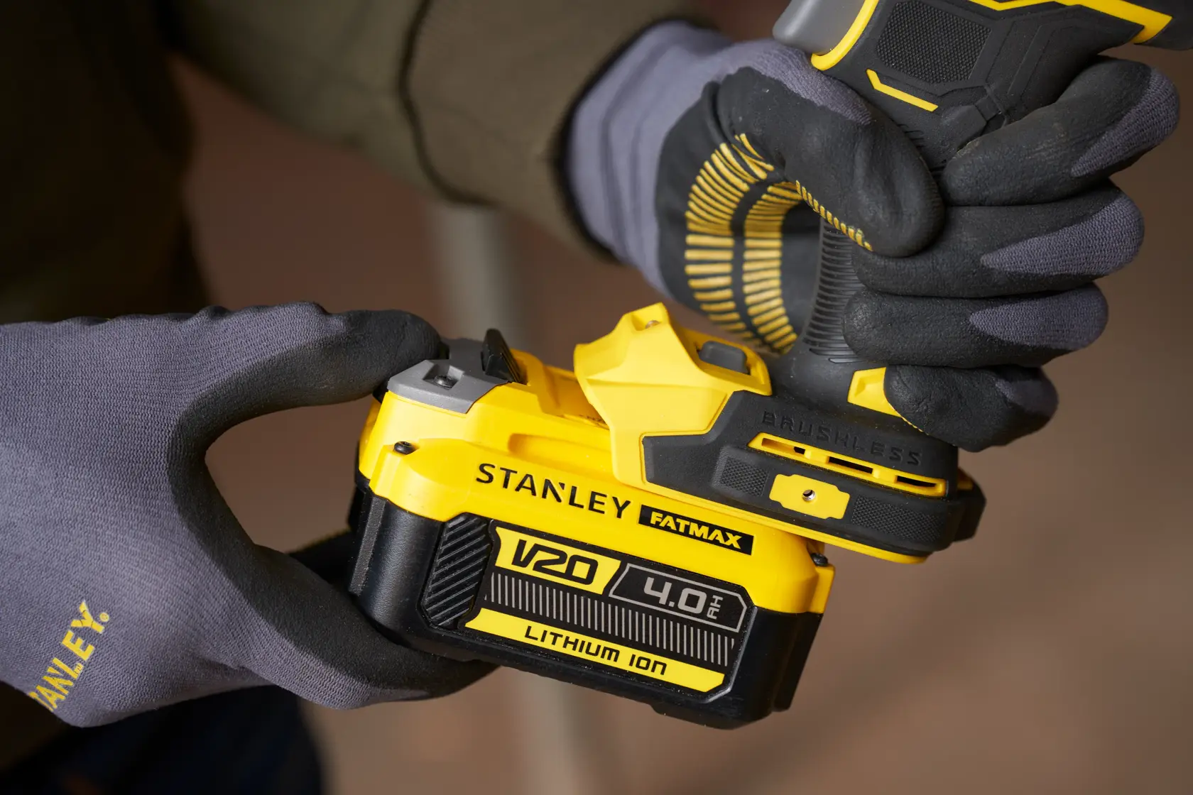Foto des kabellosen STANLEY SFMCF940M1 Bohrers mit V20 4,0Ah Lithium-Ionen-Akku, gehalten mit Handschuhen.
