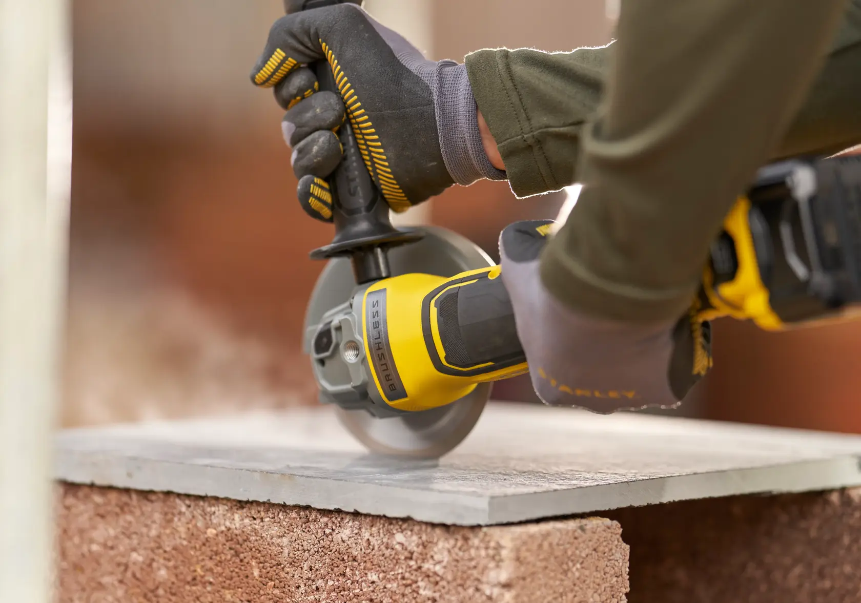 Stanley SFMCG700M2K cordless angle grinder in use, cutting stone slab, close-up photography.