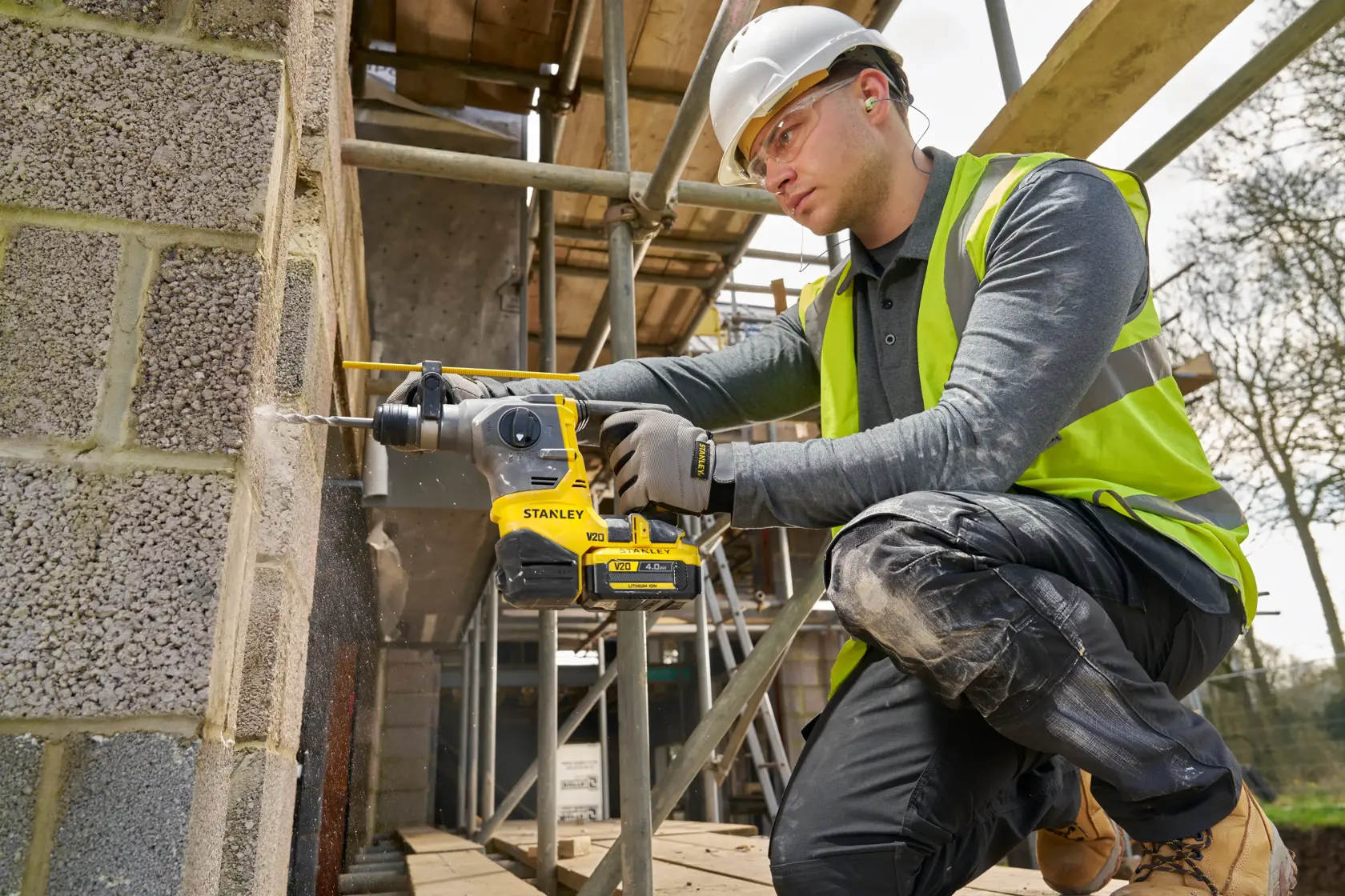 Arbeiter verwendet STANLEY SFMCH910B Akku-Bohrhammer an einer Betonwand auf einer Baustelle.