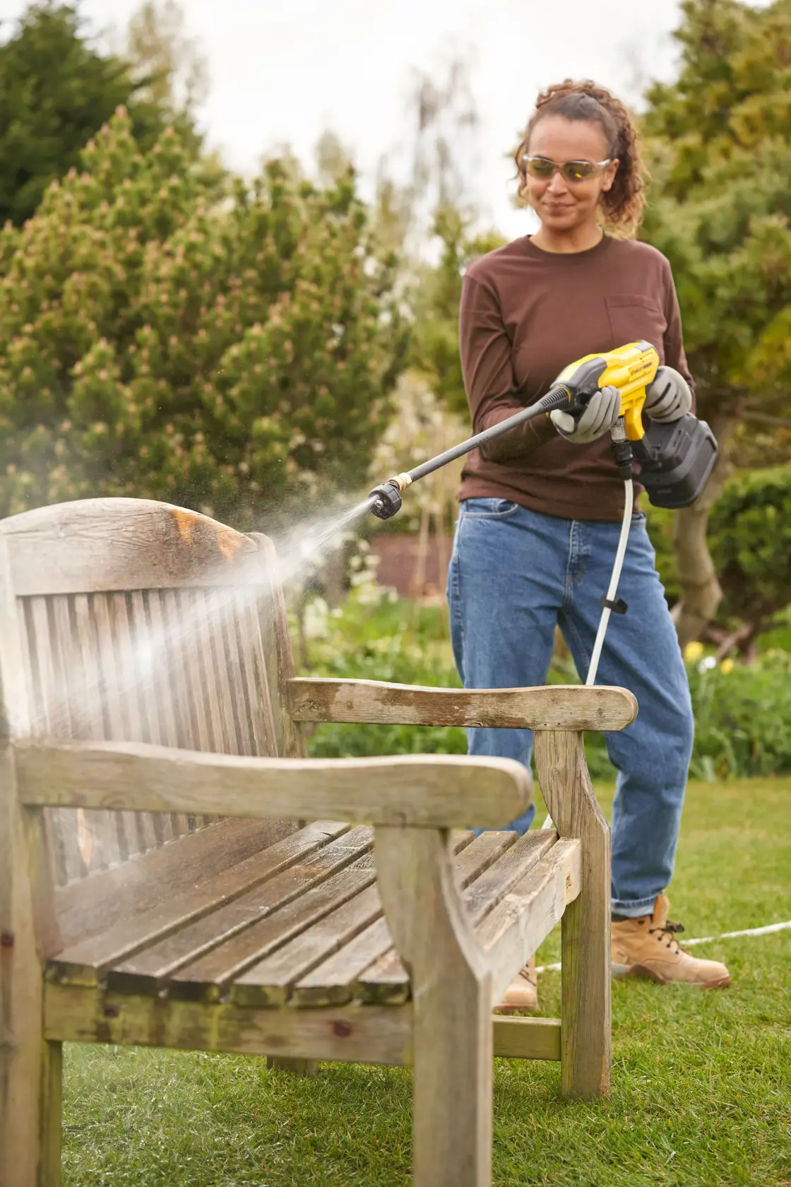 STANLEY SFMCPC93M1 pressure washer cleaning wooden bench outdoors, product in use, garden setting.