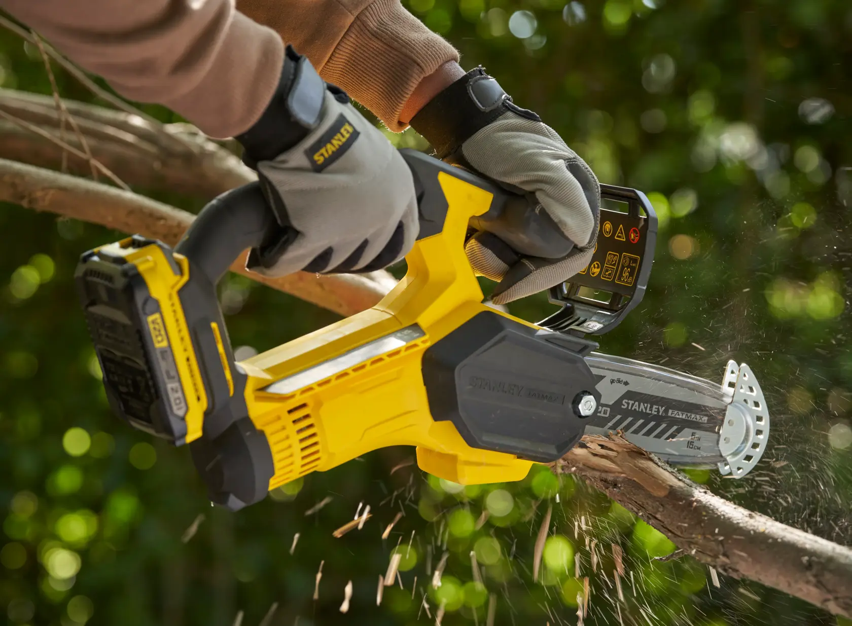 Foto der STANLEY SFMCPS415B Akku-Astschere beim Schneiden eines Astes, Benutzer mit Handschuhen im Freien.