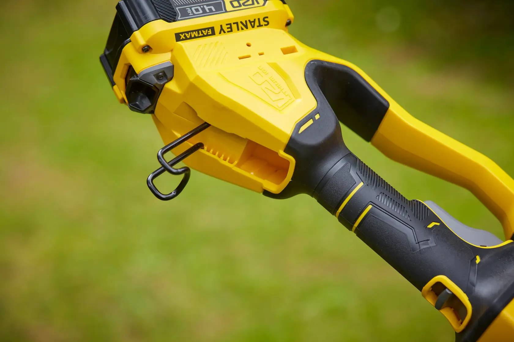 Photo of STANLEY SFMCPS620M1 chainsaw handle with black and yellow ergonomic grip, side outdoor view.