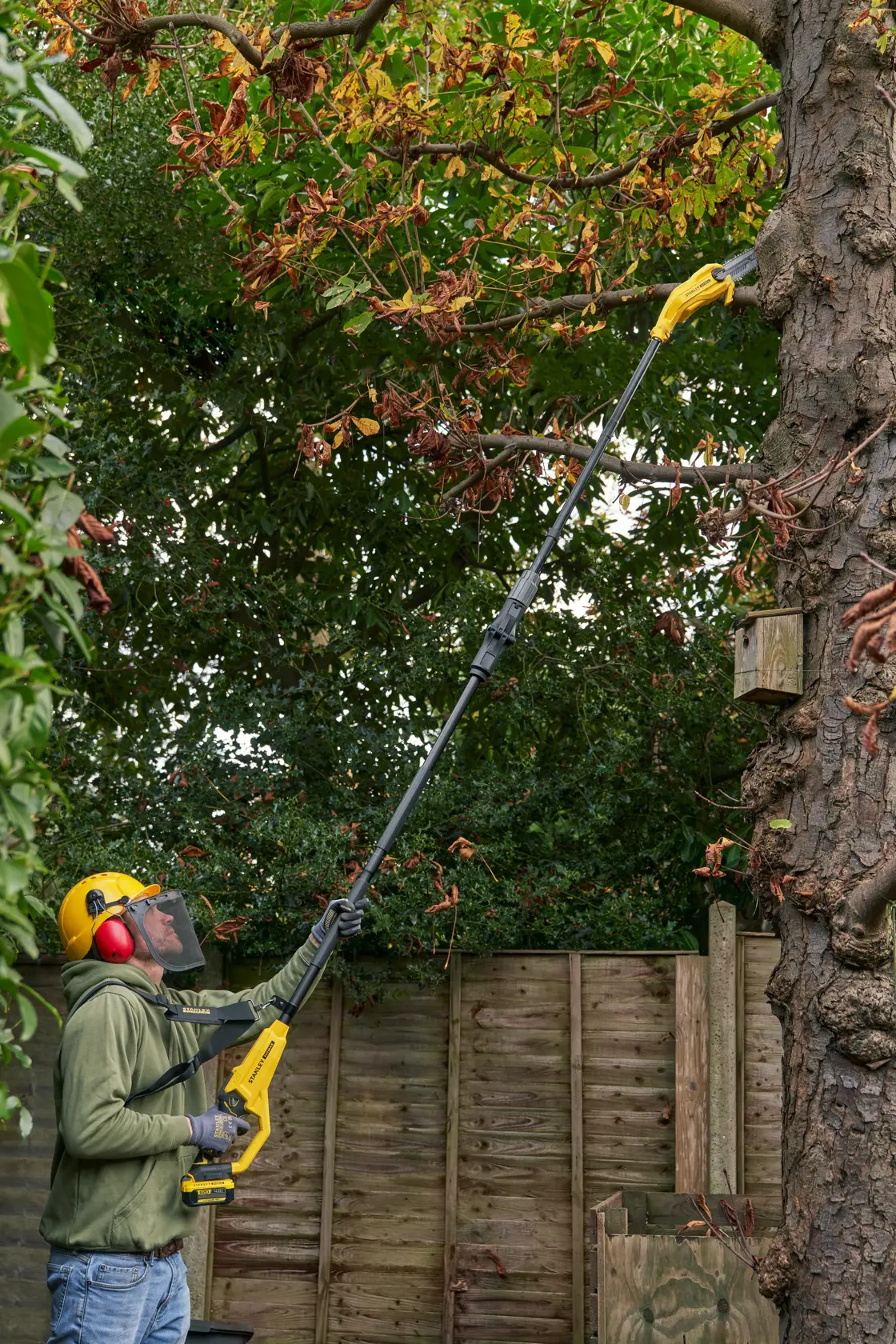 STANLEY SFMCPS720B-XJ Hochentaster zum Schneiden hoher Äste in einem Garten verwendet.