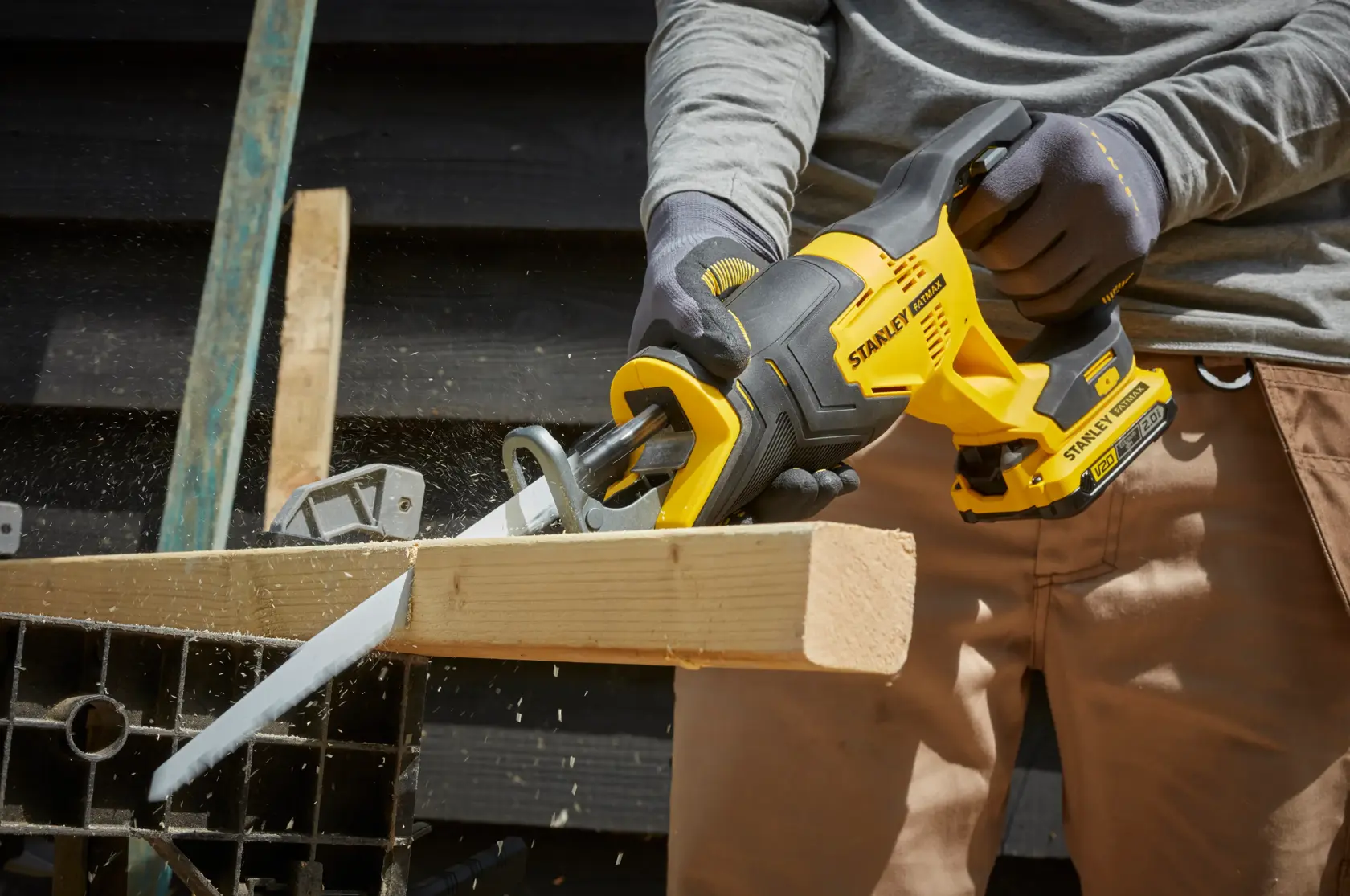 STANLEY SFMCS300D2K reciprocating saw in use cutting wood, close-up side view, yellow and black cordless tool.