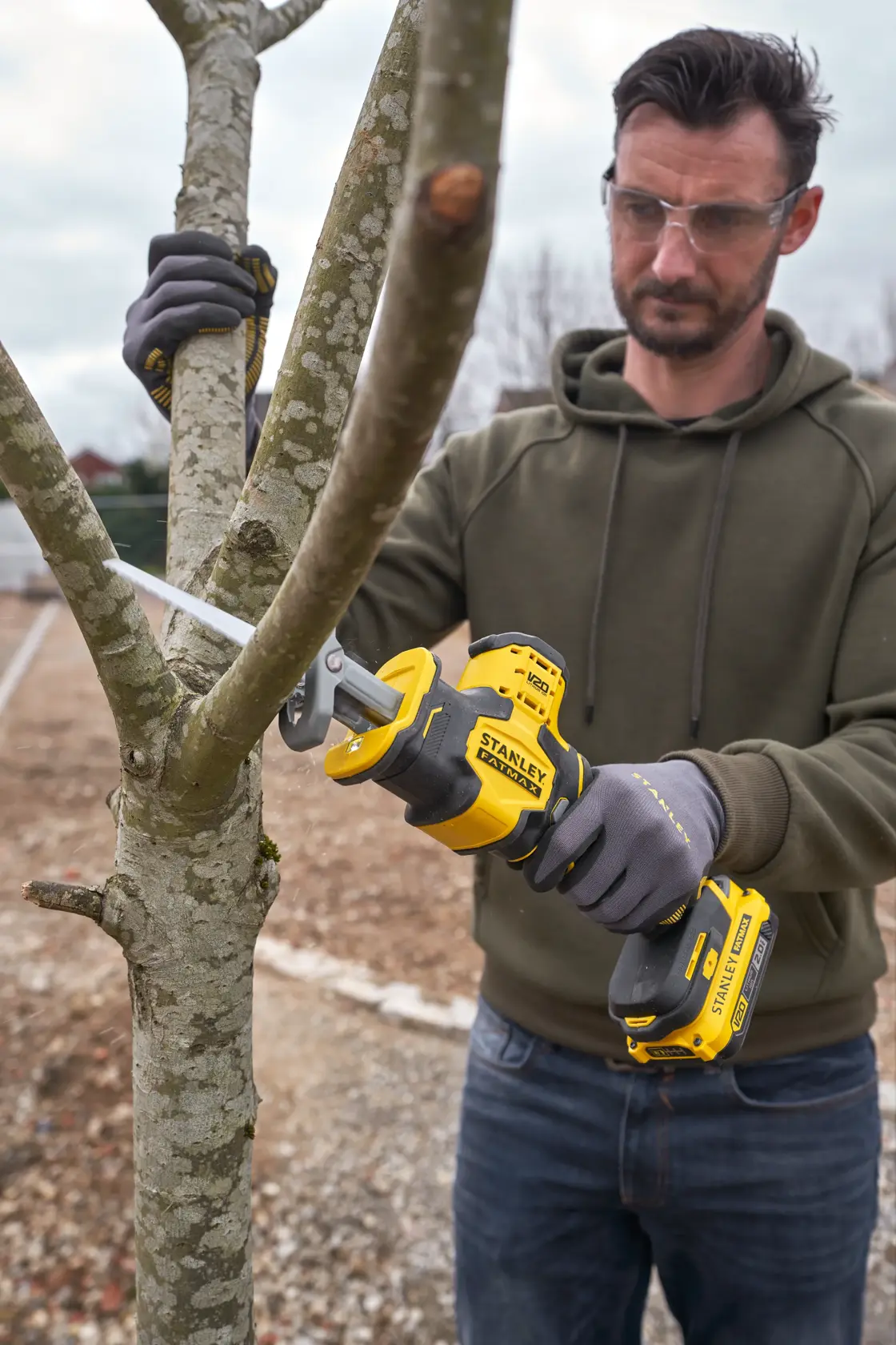 Photo of STANLEY SFMCS305B cordless reciprocating saw being used to cut tree branch outdoors.