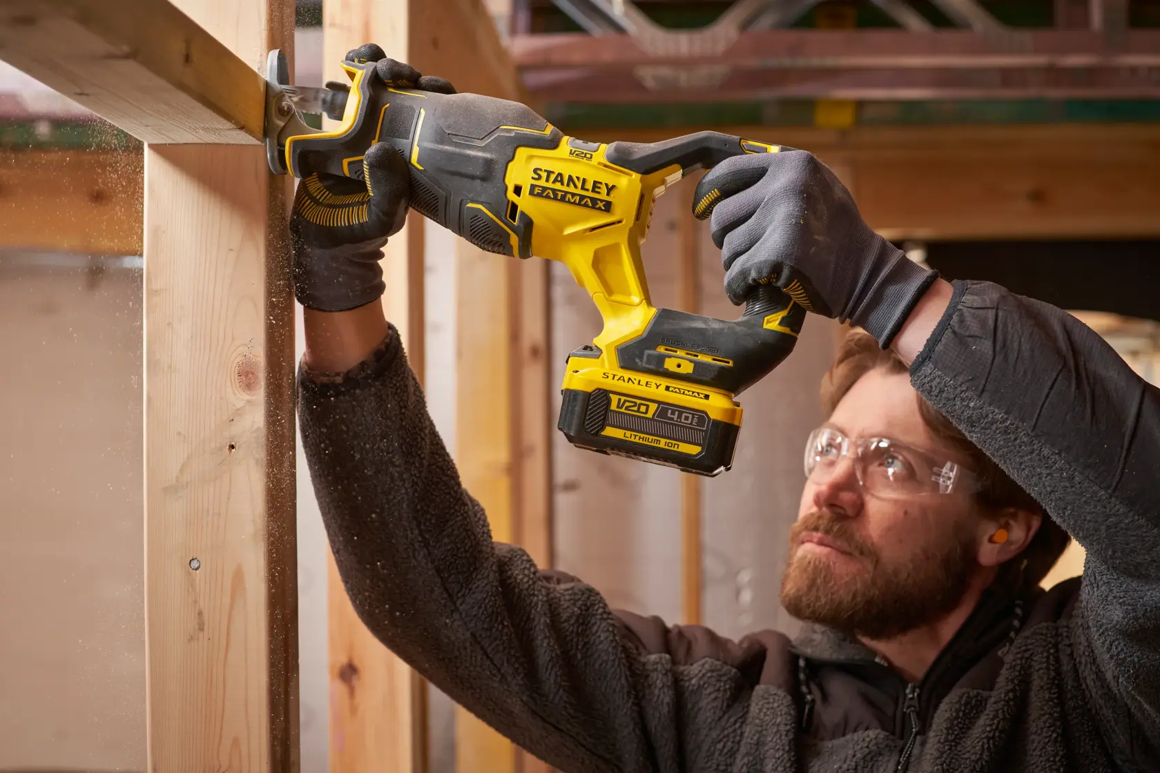 Photo of STANLEY SFMCS311B-XJ cordless reciprocating saw cutting wood, held by person wearing gloves.