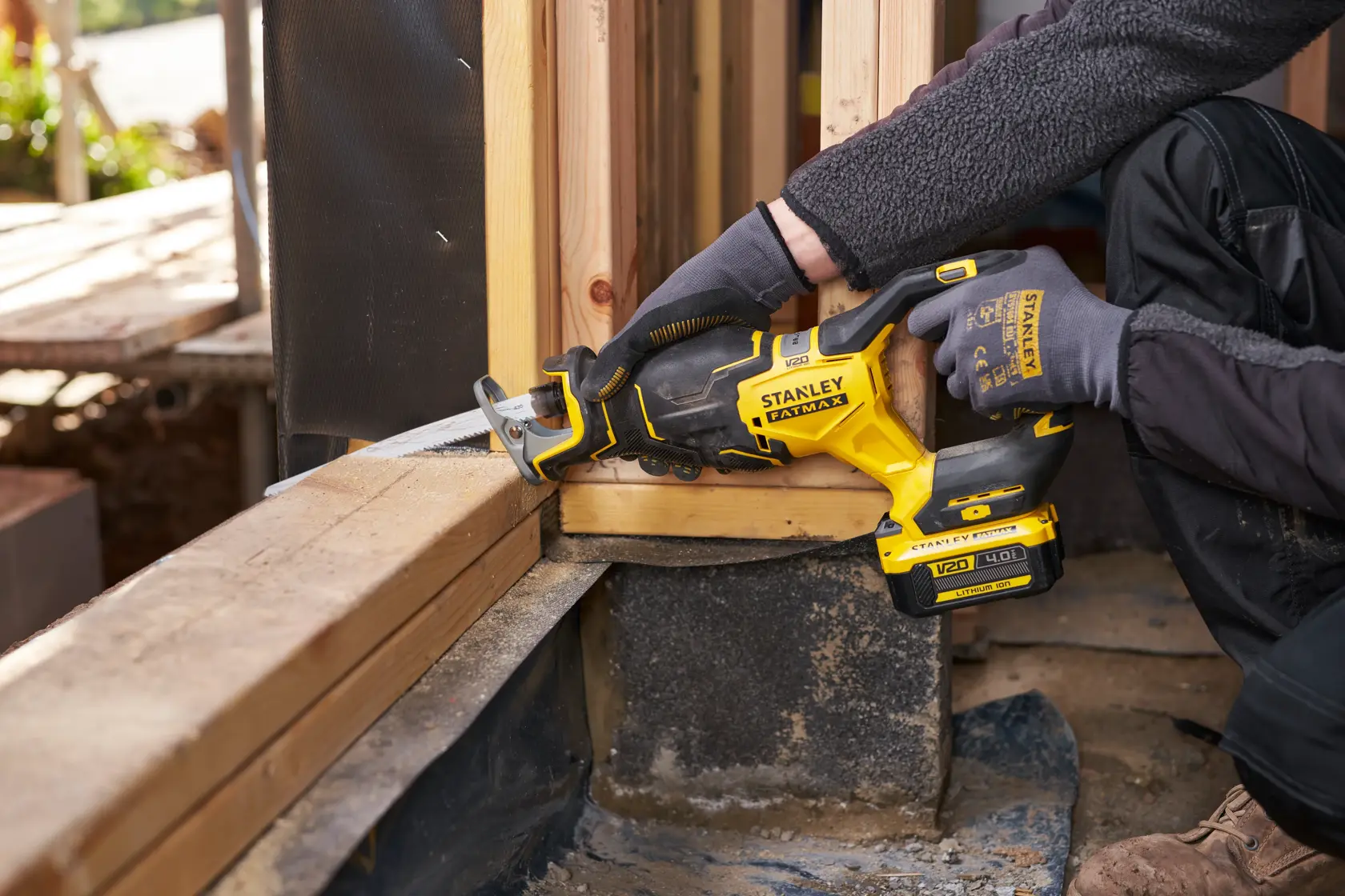 Stanley SFMCS311B-XJ Akku-Säbelsäge schneidet Holz auf einer Baustelle, Seitenansicht.