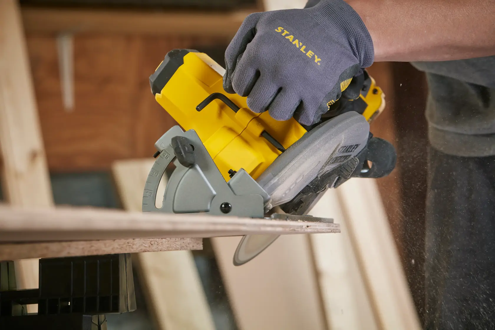STANLEY SFMCS500M2K cordless circular saw cutting wood, side angle, with branded work glove.