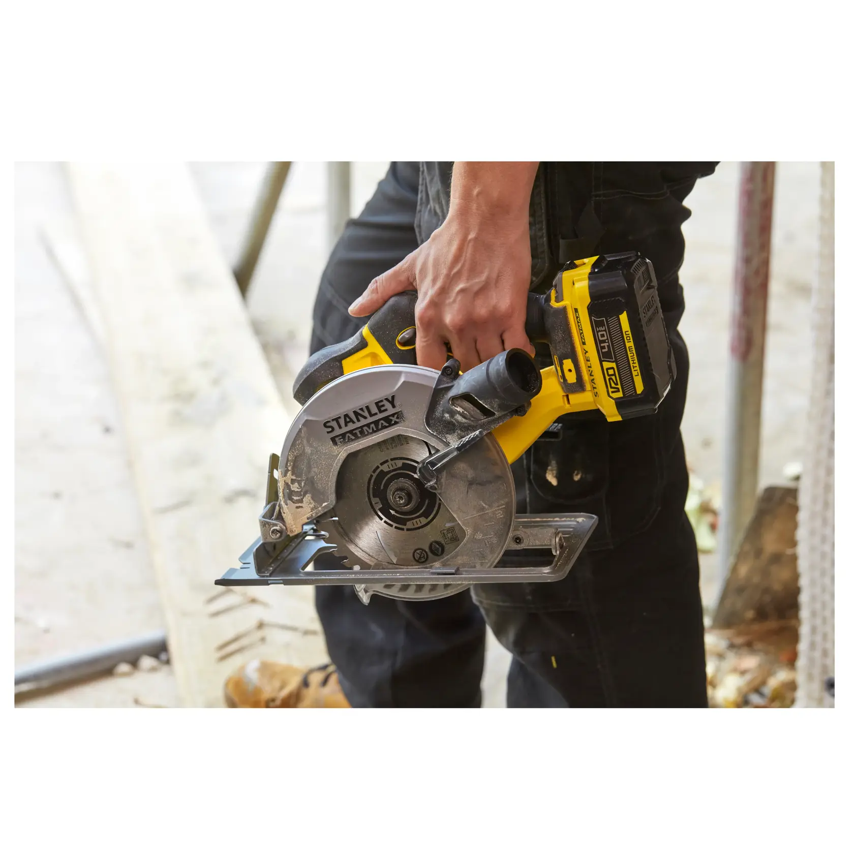 STANLEY SFMCS500M2K cordless circular saw held by worker, yellow and silver, construction setting.