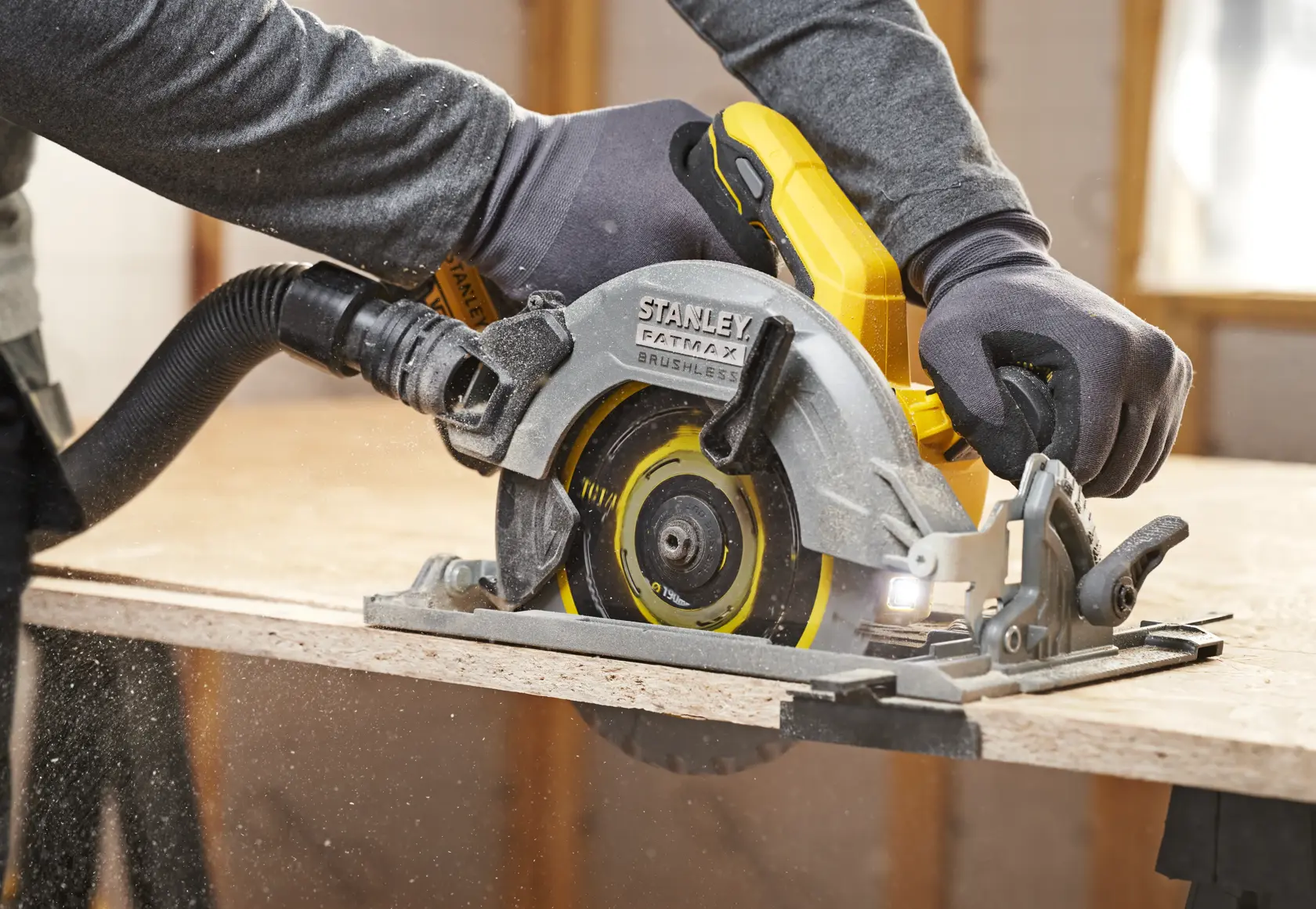 STANLEY SFMCS551B Kreissäge im Einsatz beim Schneiden von Holz, Nahaufnahme von Seite mit Sägeblatt und ergonomischem Griff.