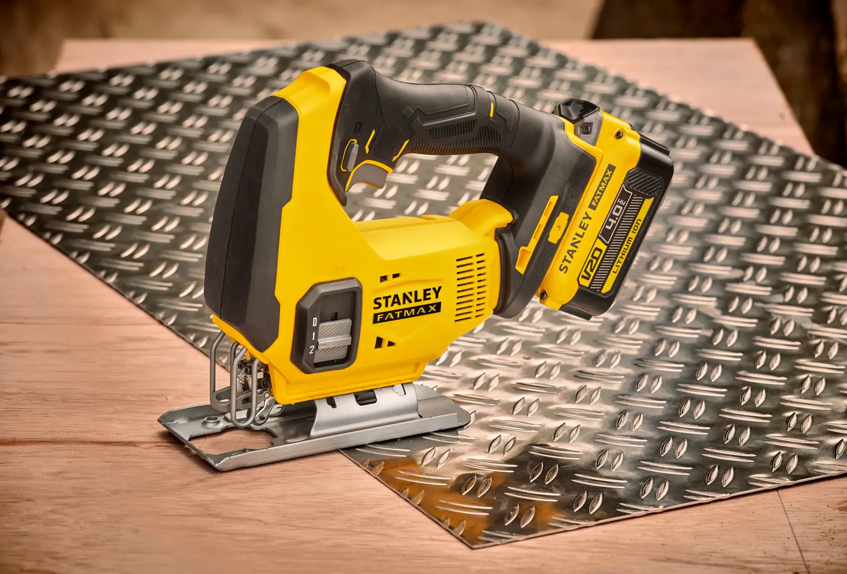 STANLEY SFMCS600M2K jigsaw tool on textured metal sheet, yellow and black design, side view.