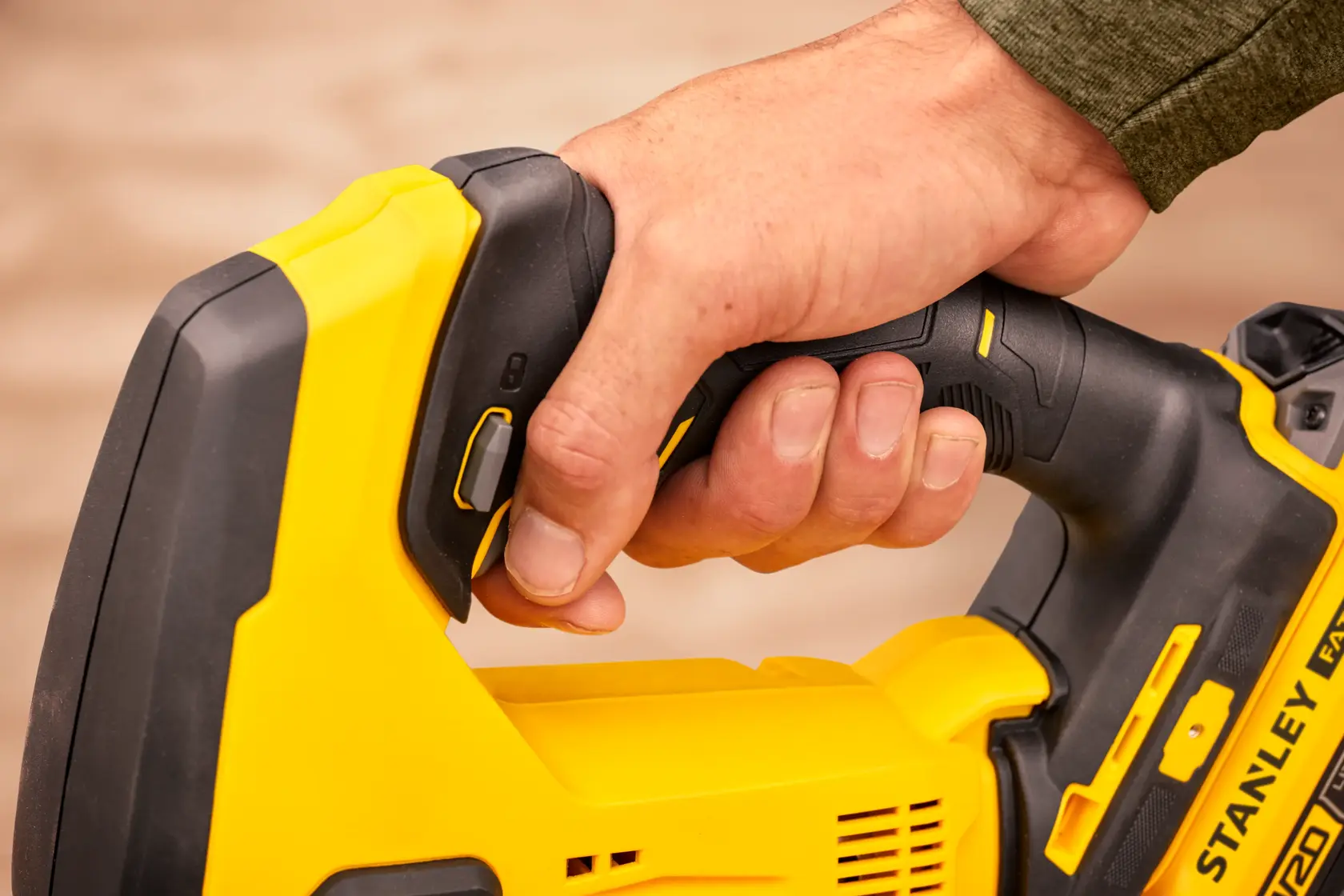 Close-up of a hand gripping the STANLEY SFMCS600M2K cordless reciprocating saw handle.