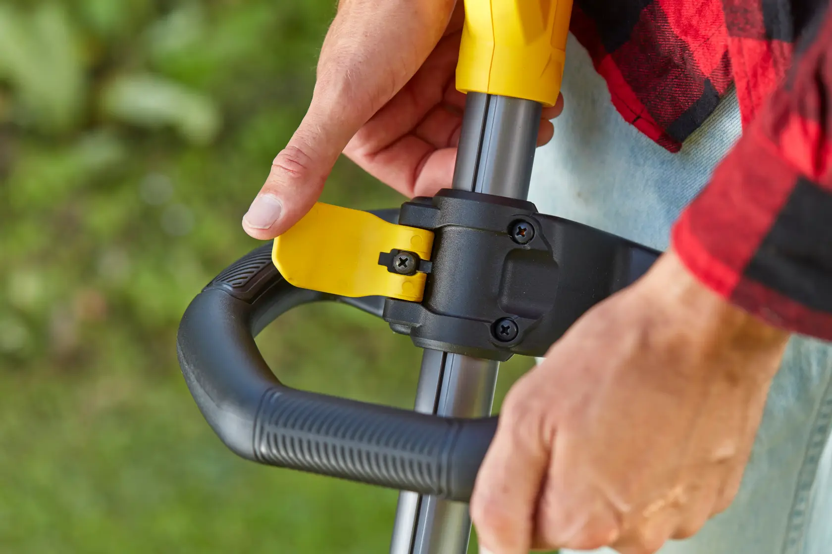 STANLEY SFMCSTB933M trimmer adjustable handle close-up, showing yellow lever and black grip outdoors.