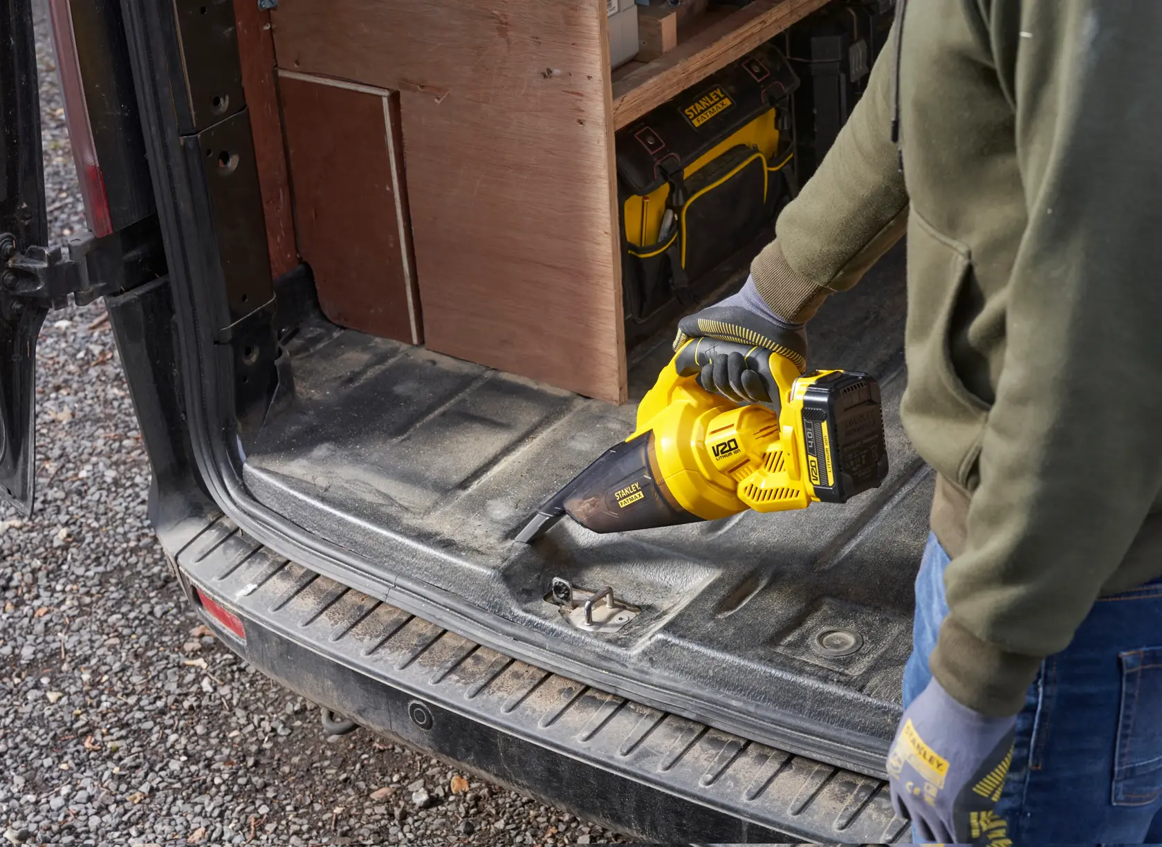 STANLEY SFMCVH001B Handstaubsauger im Einsatz zur Reinigung eines Fahrzeugkofferraums, gelb und schwarz.