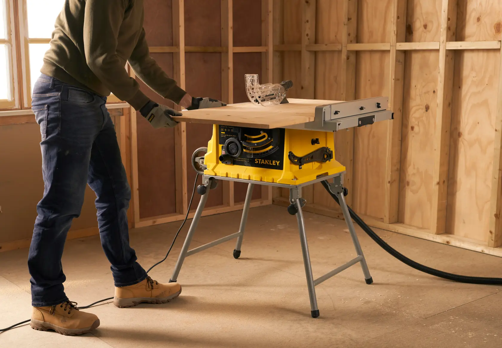 STANLEY SST1800 Tischkreissäge im Einsatz auf Baustelle, gelbes Gehäuse, erweiterte Arbeitsfläche, Holz wird gesägt.