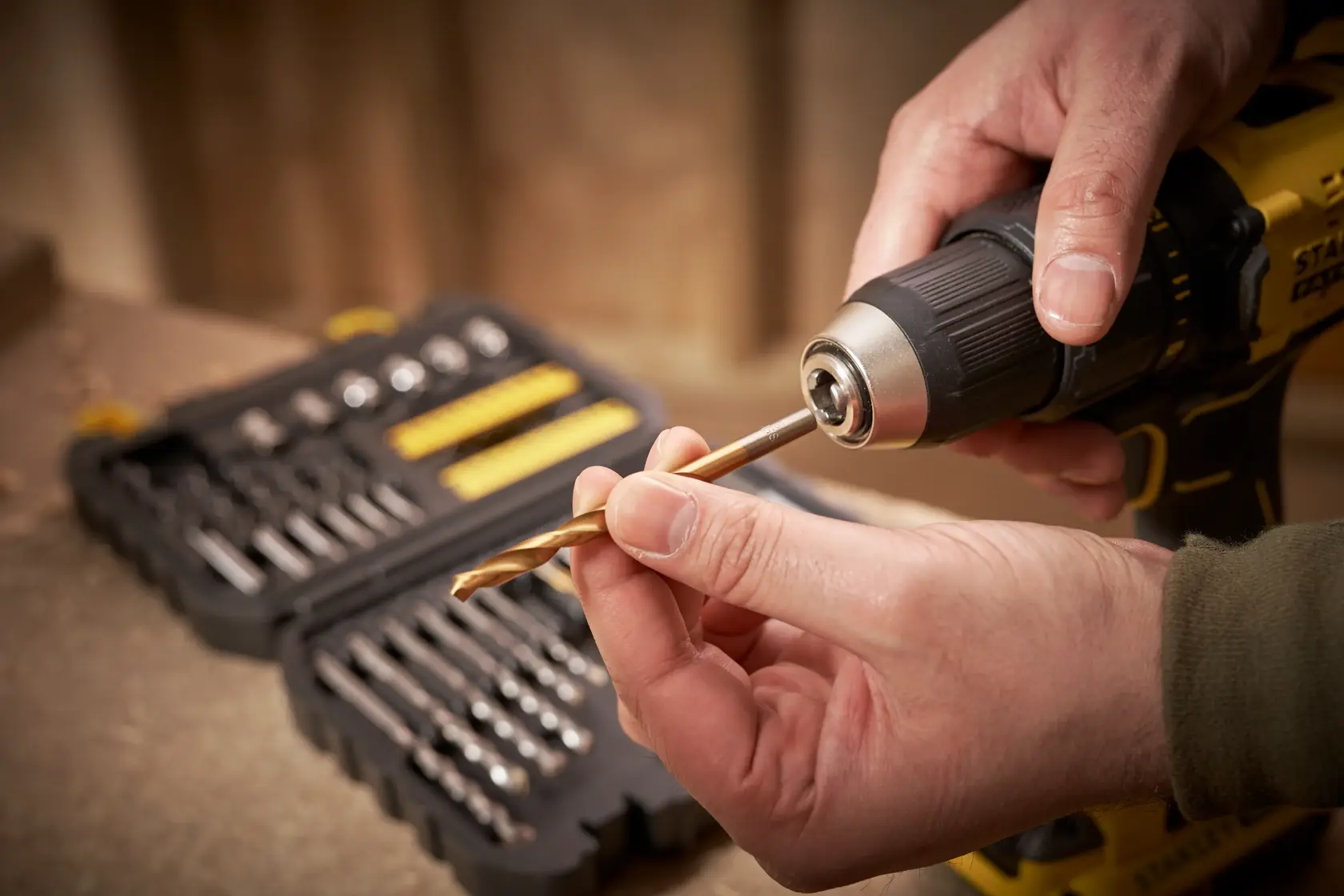STANLEY STA88546 drill bit set with yellow box, drill and hand inserting a bit, close-up photography.