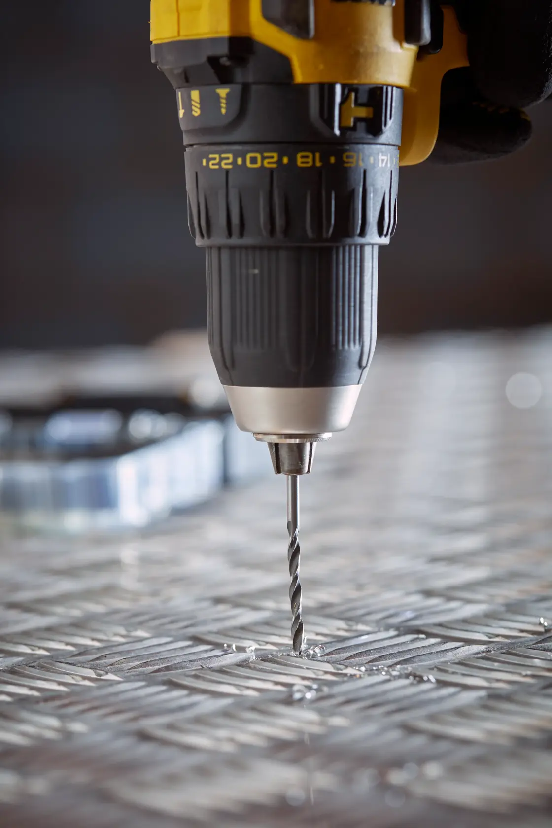 Nahaufnahme STANLEY STA88553 Bohrmaschine beim Bohren einer Metalloberfläche, Elektrowerkzeug schwarz-gelb.
