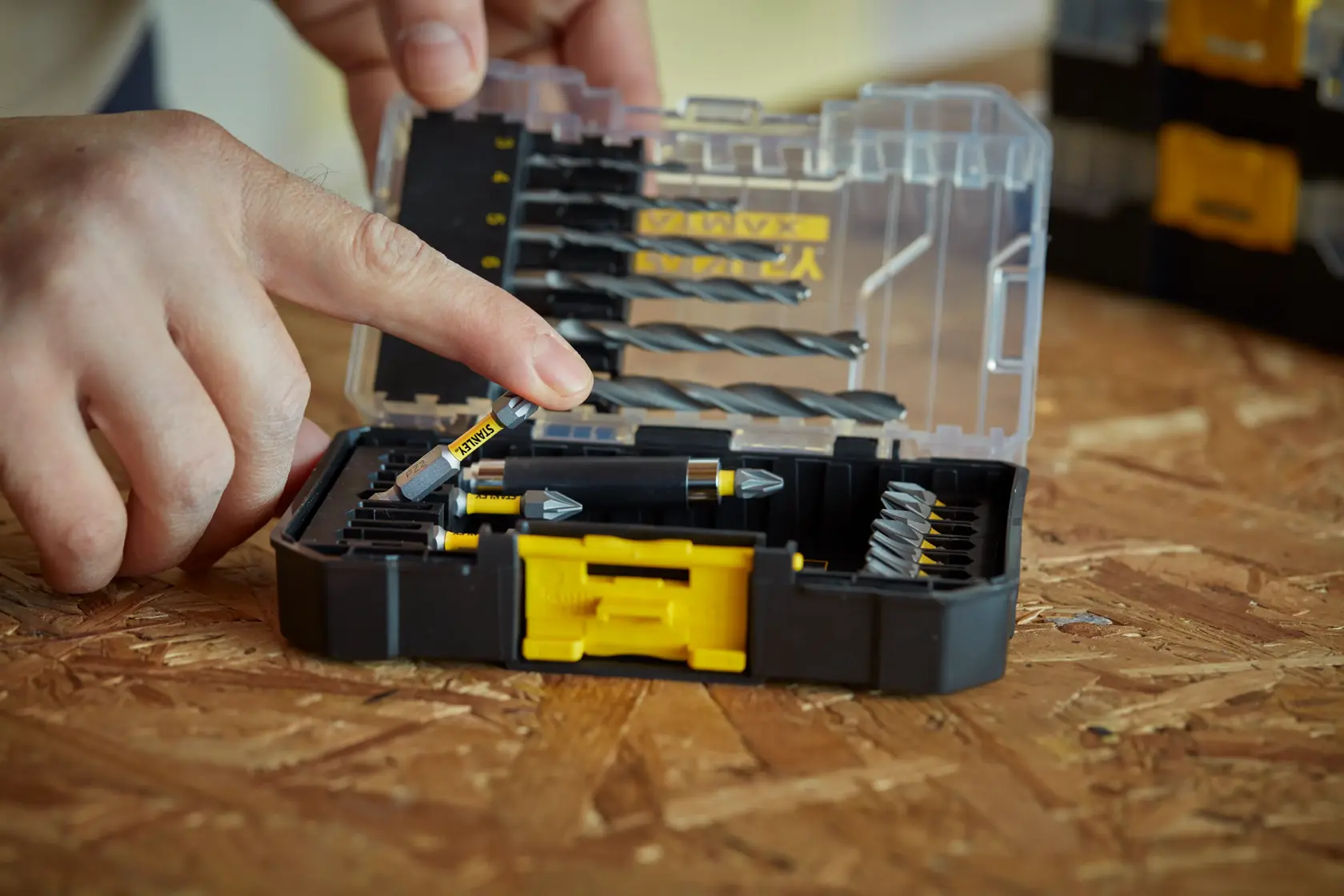STANLEY STA88554-XJ Bohrer-Set in transparenter Kunststoffbox, Person wählt Bohrer aus, Kategorie Fotografie.