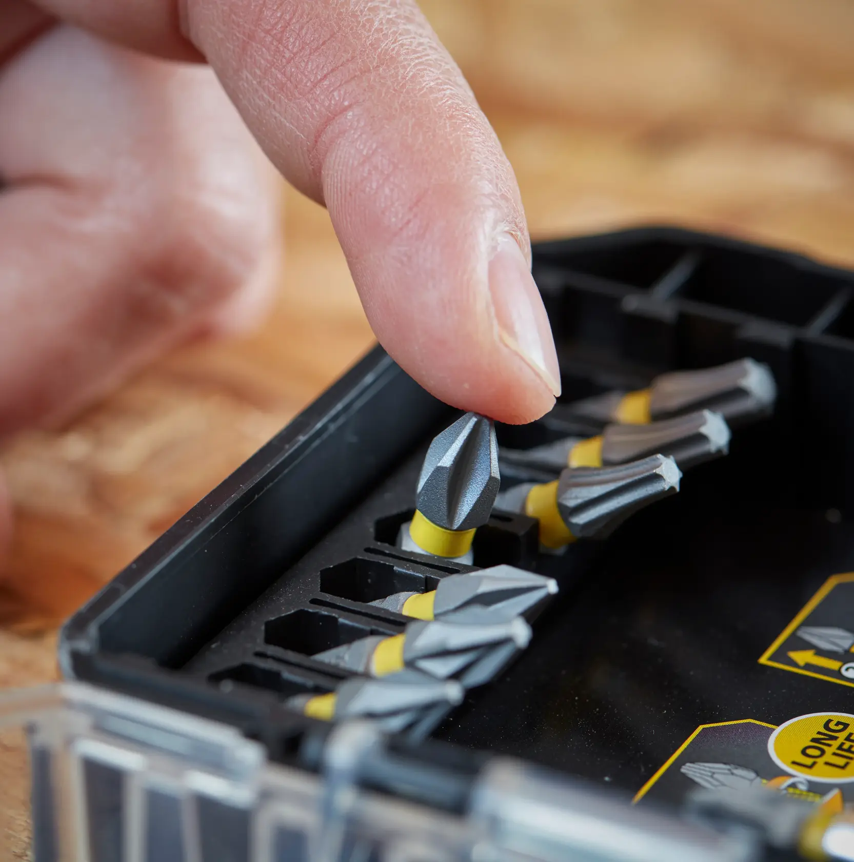 STANLEY STA88558 Schrauber-Bit-Set, Nahaufnahme eines Fingers, der einen grauen und gelben Bit aus dem Kasten nimmt.