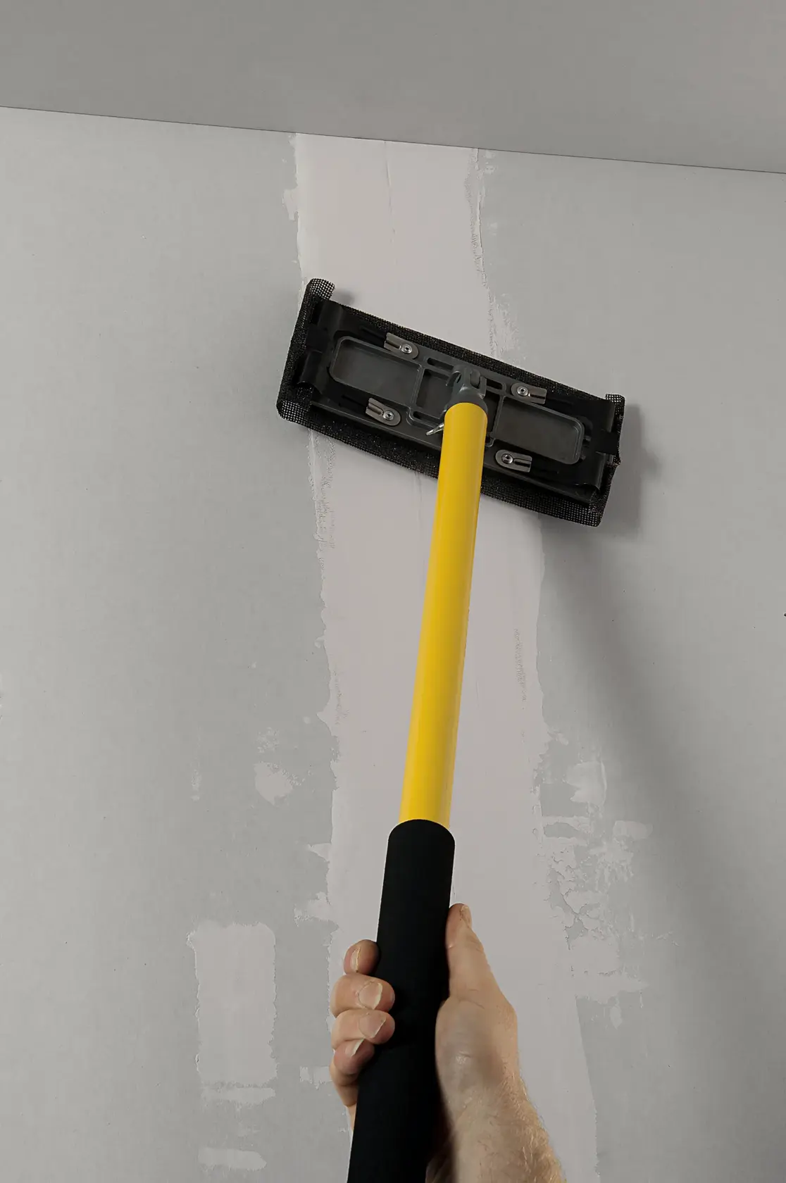 STANLEY STHT0-05928 Trockenbauschleifer mit gelbem Griff, genutzt an der Decke, Nahaufnahme.