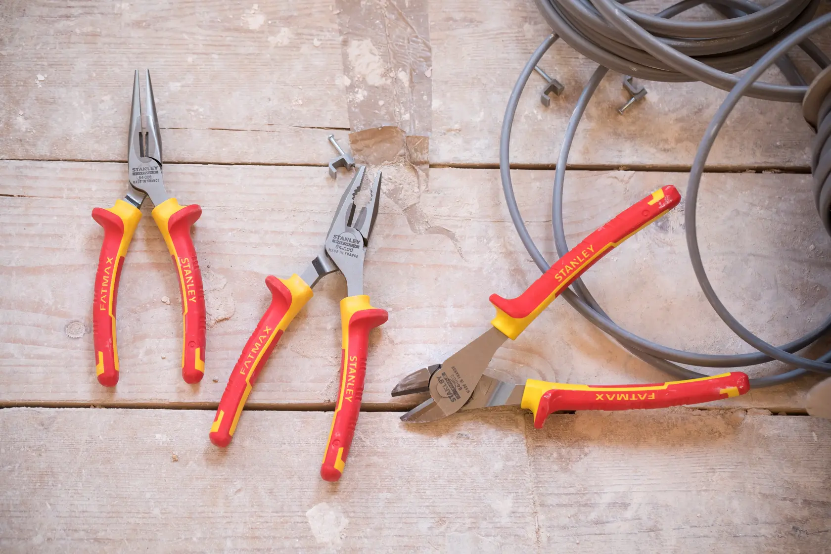 Photo of STANLEY STHT0-73920 pliers set with red and yellow handles on a wooden surface, side angle.