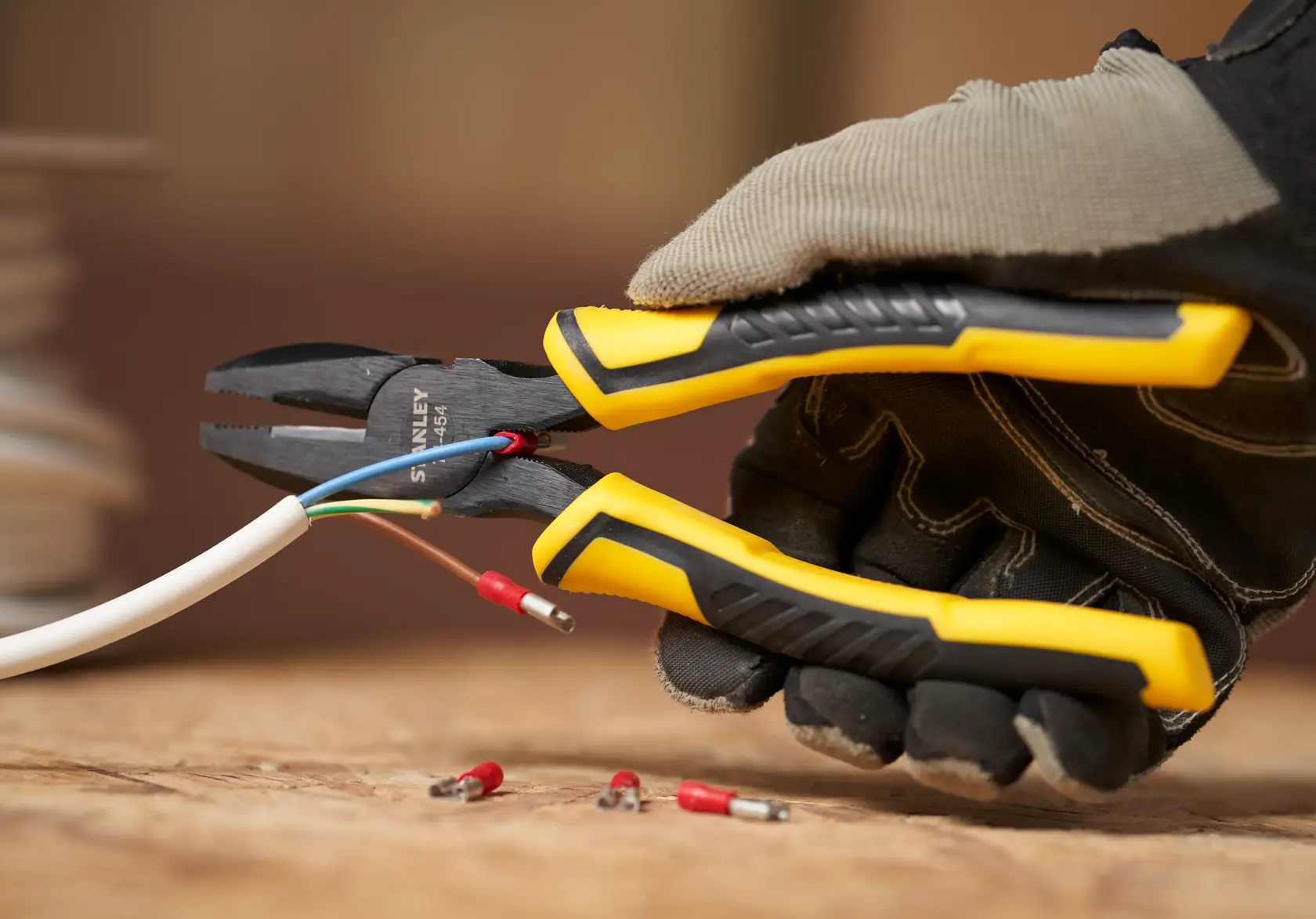 STANLEY STHT0-74456 diagonally angled pliers with yellow and black grip cutting electrical wire.