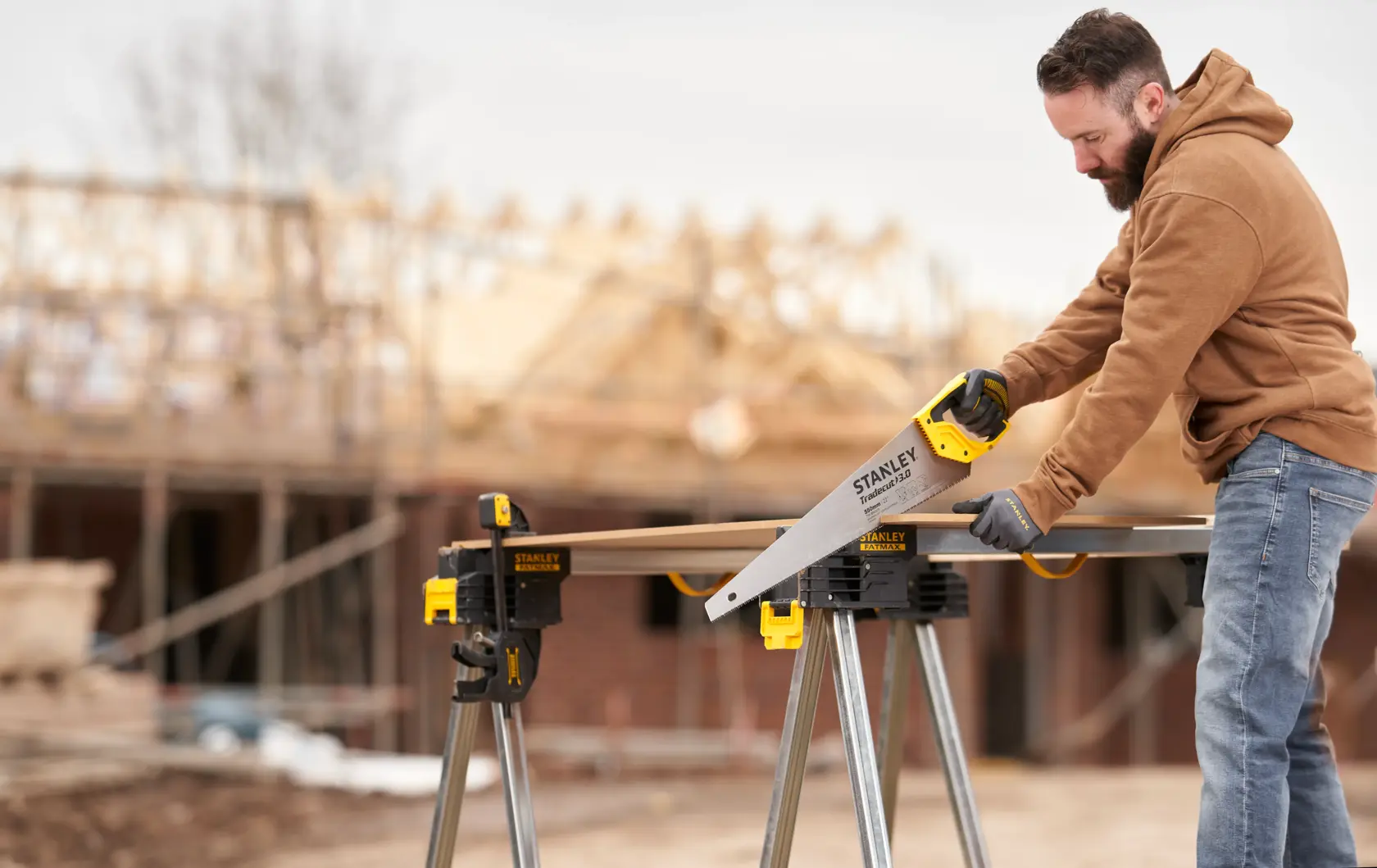STANLEY STHT1-20352 Handsäge im Außenbereich einer Baustelle, Holz wird auf Werkbank gesägt.