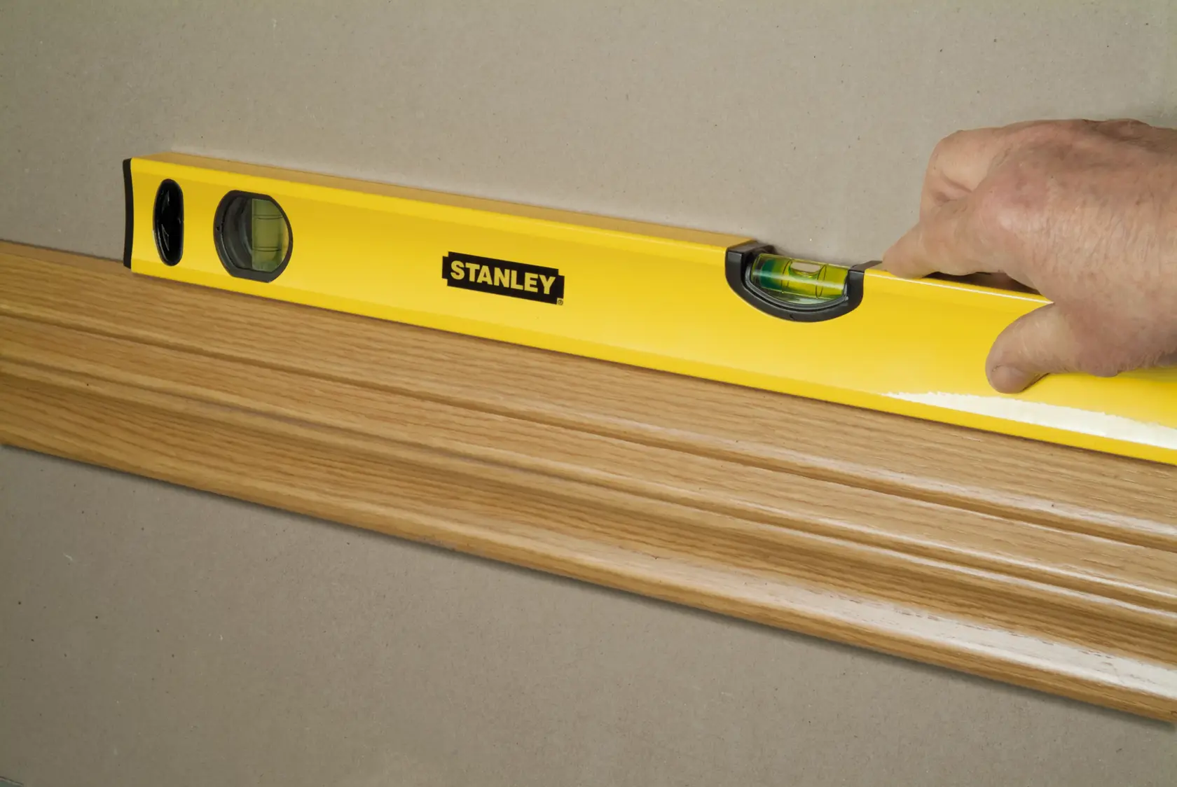 STANLEY STHT1-43103 Wasserwaage prüft Ausrichtung an Holzleiste, seitliche Nahaufnahme.