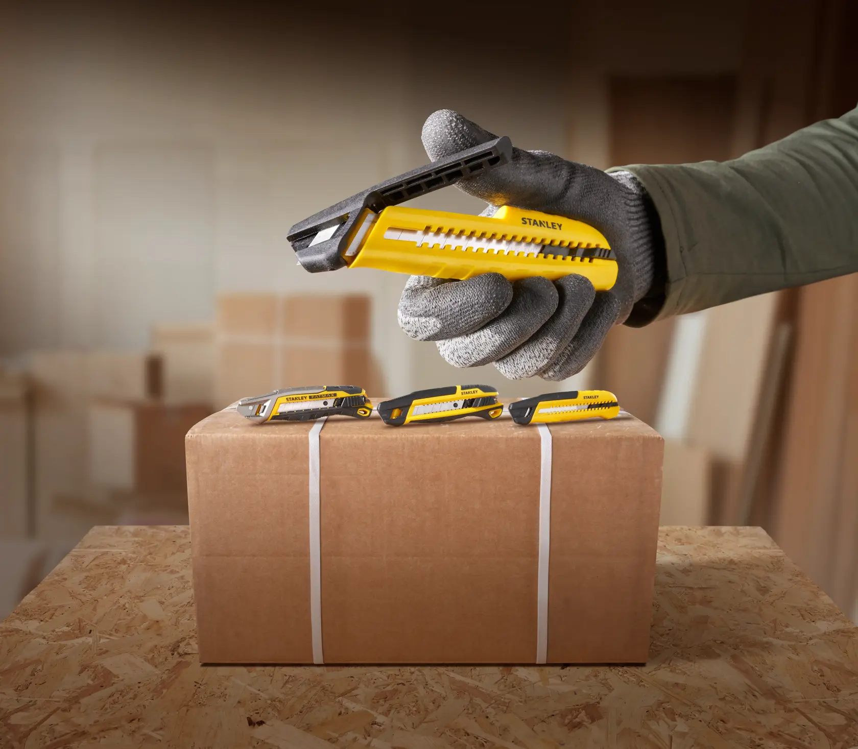 STANLEY Cuttermesser STHT10489, STHT10489-0 gelb schwarz auf Box, Hand mit Handschuh, Fotografie.