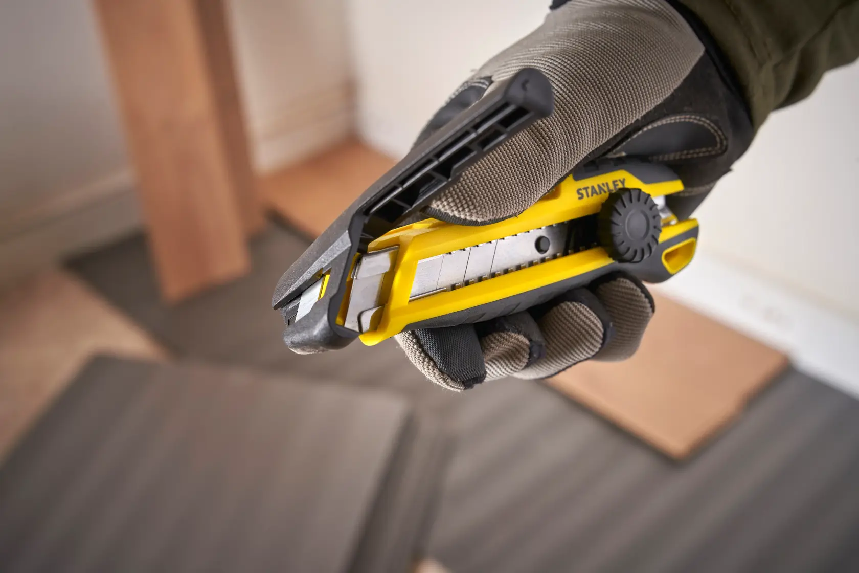 Foto des STANLEY STHT10500-0 Cuttermessers mit segmentierter Klinge, gelb und schwarz, in behandschuhter Hand.