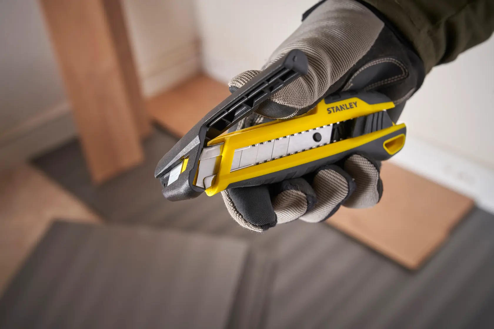 Foto des STANLEY STHT10501-0 Universalmessers, gelb und schwarz, in behandschuhter Hand, Produktnahaufnahme.