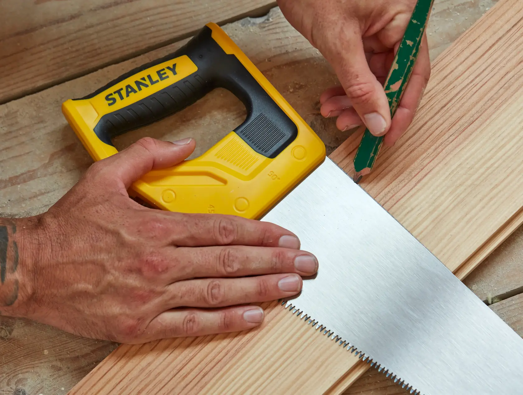 STANLEY STHT20351-1 Handsäge mit gelbem und schwarzem Griff auf Holz, Nahaufnahme beim Markieren.