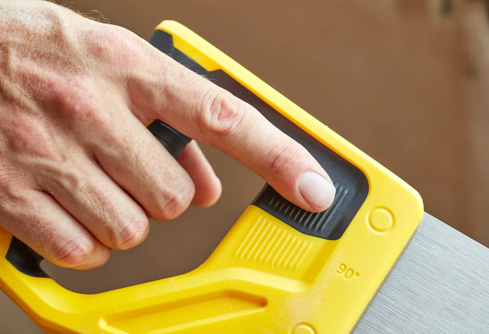 STANLEY STHT20351-1 Handsäge, Nahaufnahme des gelben Griffs und Einstellgriff, mit Finger gehalten.