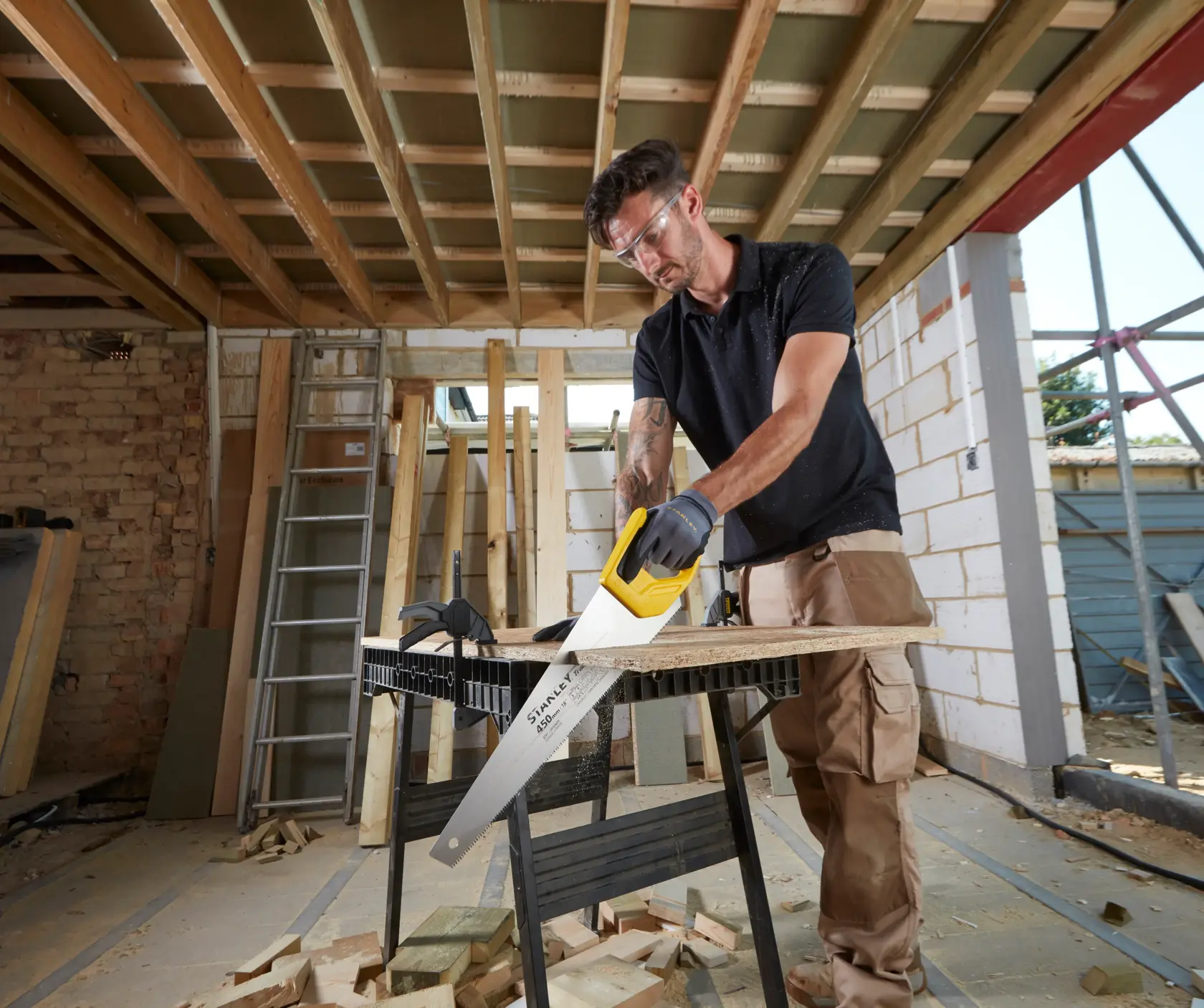 STANLEY STHT20354-1 Handsäge mit gelbem Griff beim Schneiden von Holz auf einer Baustelle.