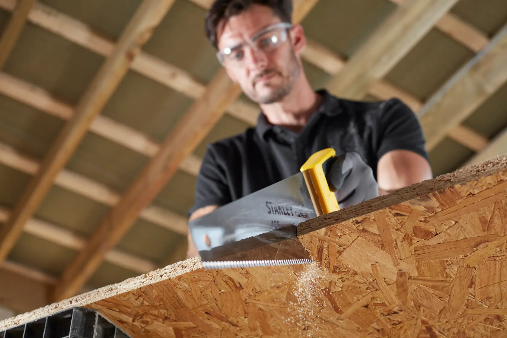 STANLEY STHT20354-1 Handsäge mit gelbem Griff schneidet Holzplatte in einer Werkstatt.