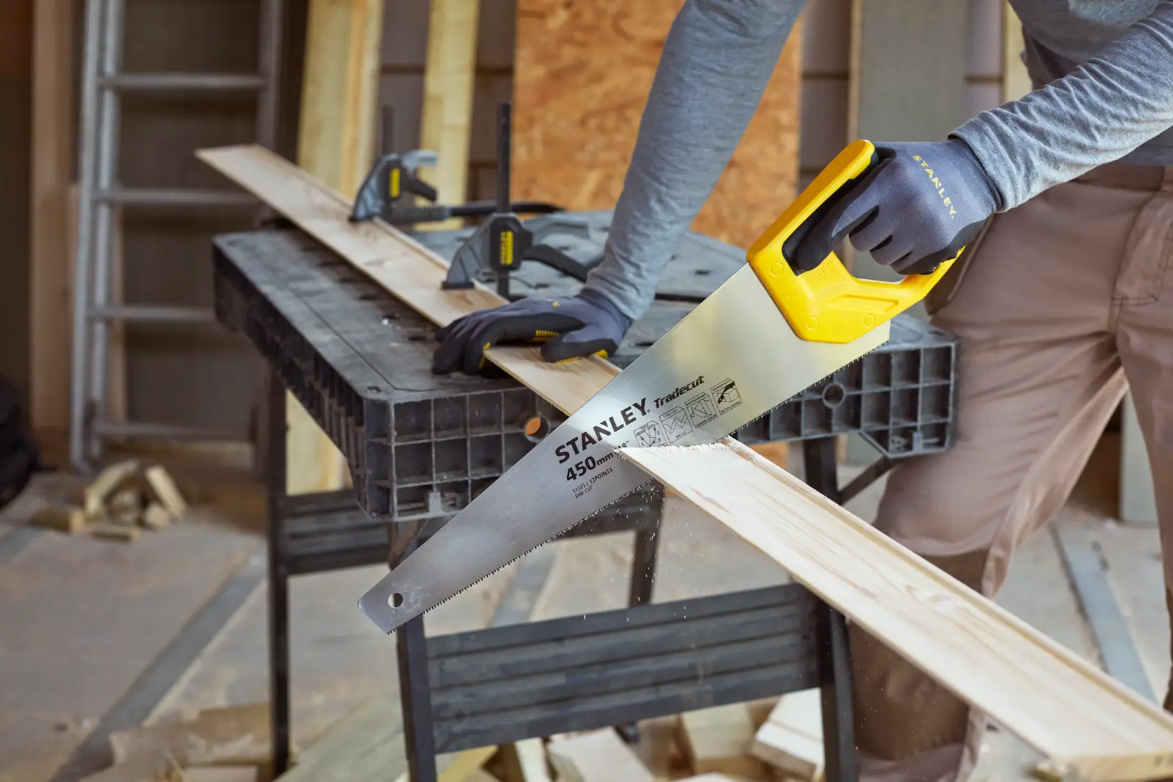 Stanley STHT20355-1 Handsäge mit gelbem Griff beim Schneiden von Holz in einer Werkstatt.