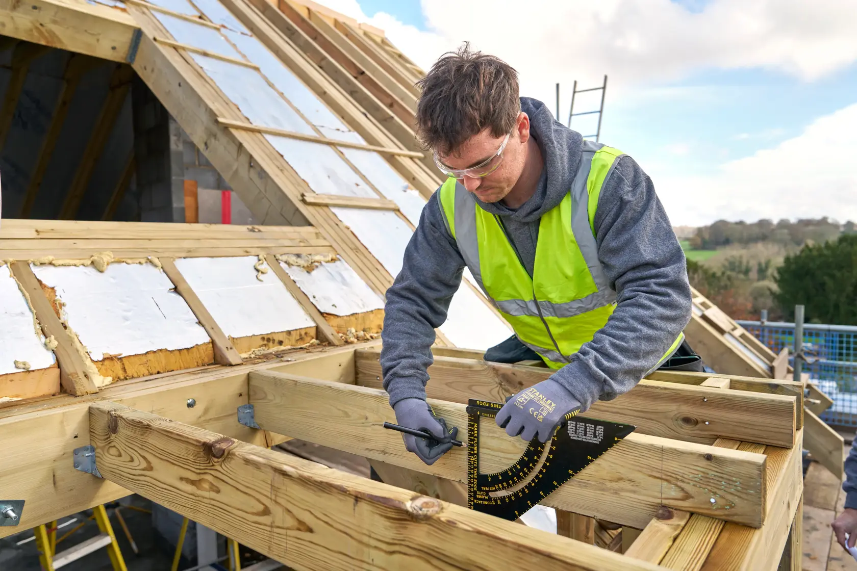 STANLEY STHT46054-0 framing square used by worker marking timber at construction site.