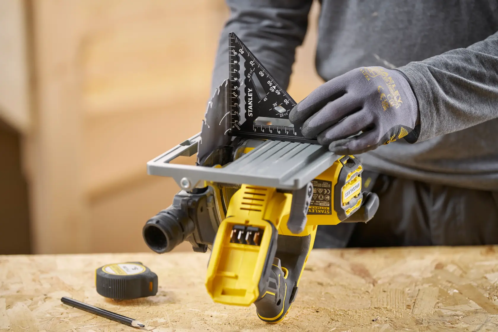 STANLEY STHT46100-0 black carpenter's square held by gloved hand on a workbench, photo shows top angle.