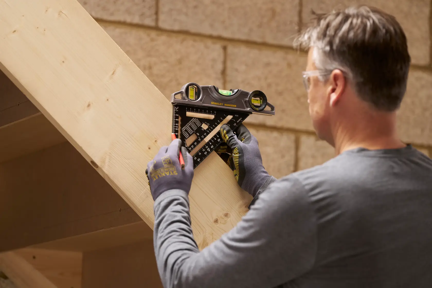 STANLEY STHT46101-0 combination square used by a person marking lines on a wooden beam.