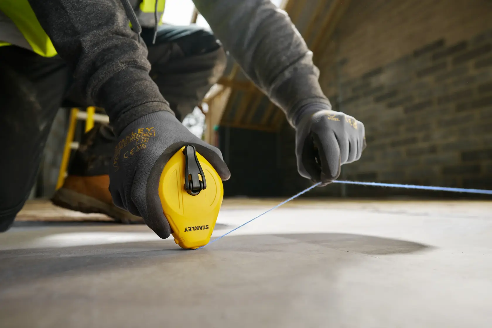 Photo of STANLEY STHT47112-0 chalk line tool in use on construction site floor.